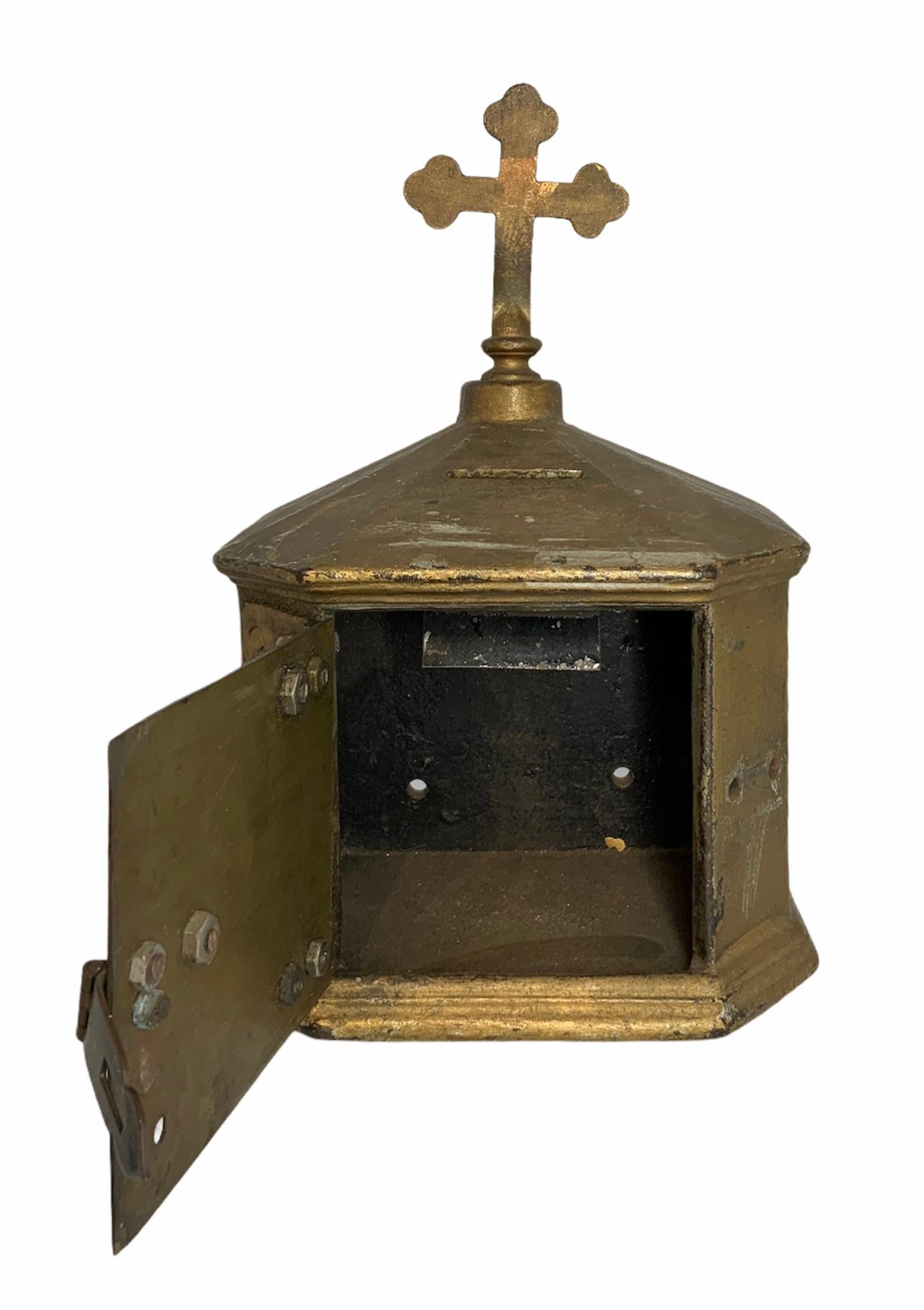 A gilt bronze Catholic Church poor box built as a pentagon. Its ceiling is adorned with a budded cross that symbolizes the Trinity. The box was usually located by the door in order for the faithful donate or provide coins and then, the priests and