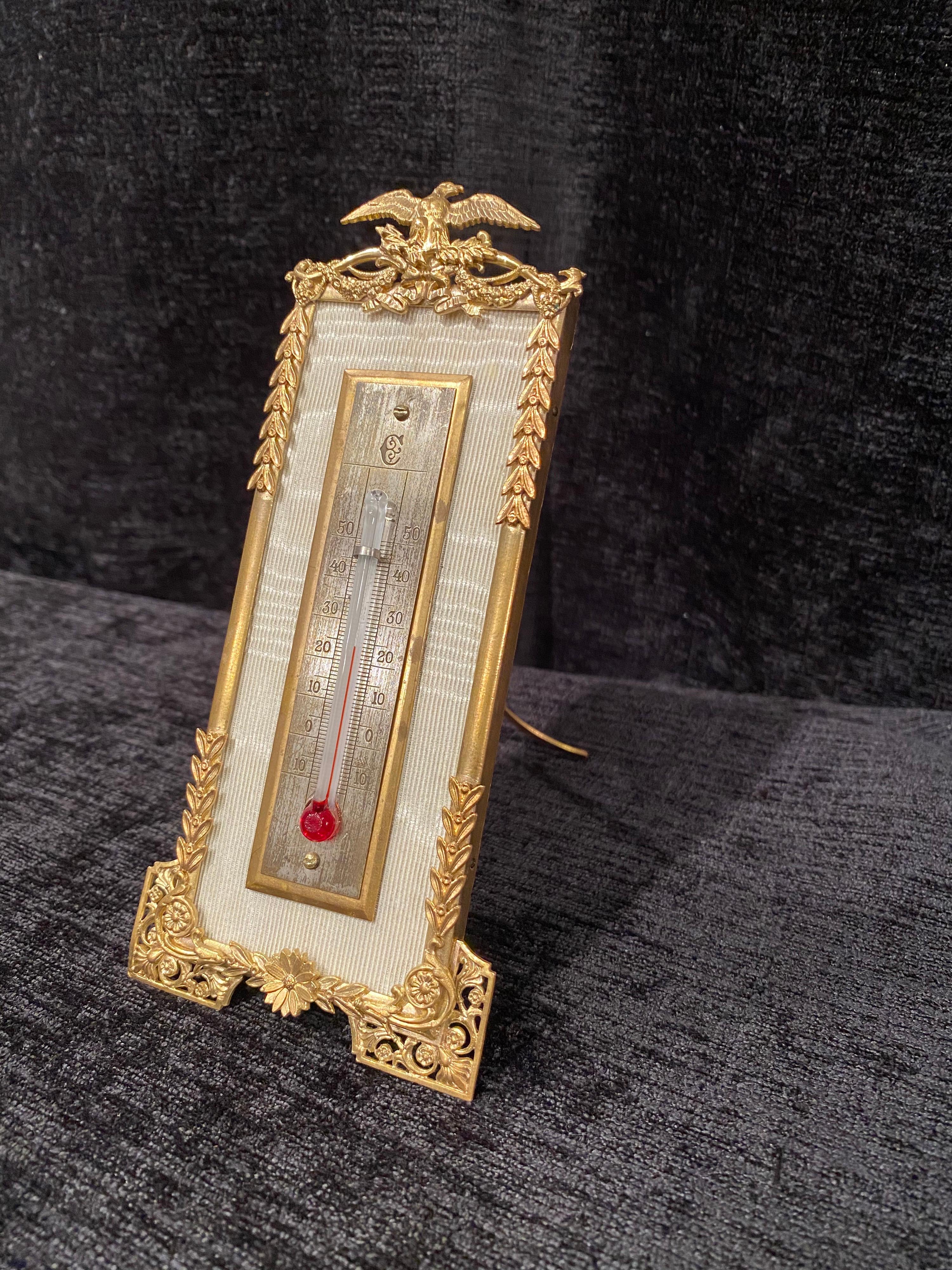 Desk or hanging thermometer
19th century, Celsius scale gilt bronze frame.
Wood panel covered in silk with a silver plated
plate mounted on a gilt-bronze plate.