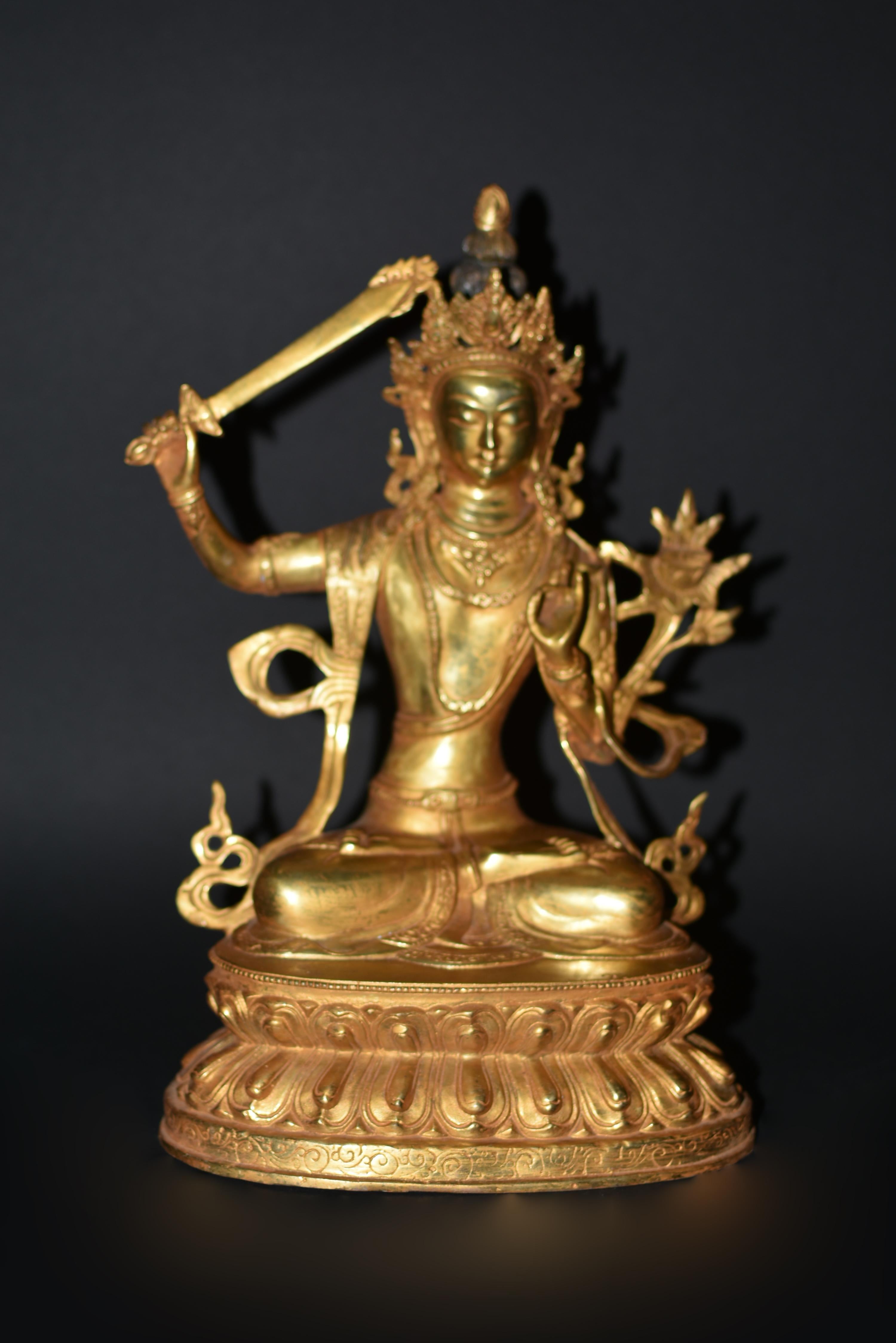 A large, beautiful gilt bronze, 6.35 lb statue of Tibetan Bodhisattva Manjushree. This special piece features Manjushree with lowered head in the motion of observing and taking action. Seated in vajrasana on a double lotus throne, in his right hand