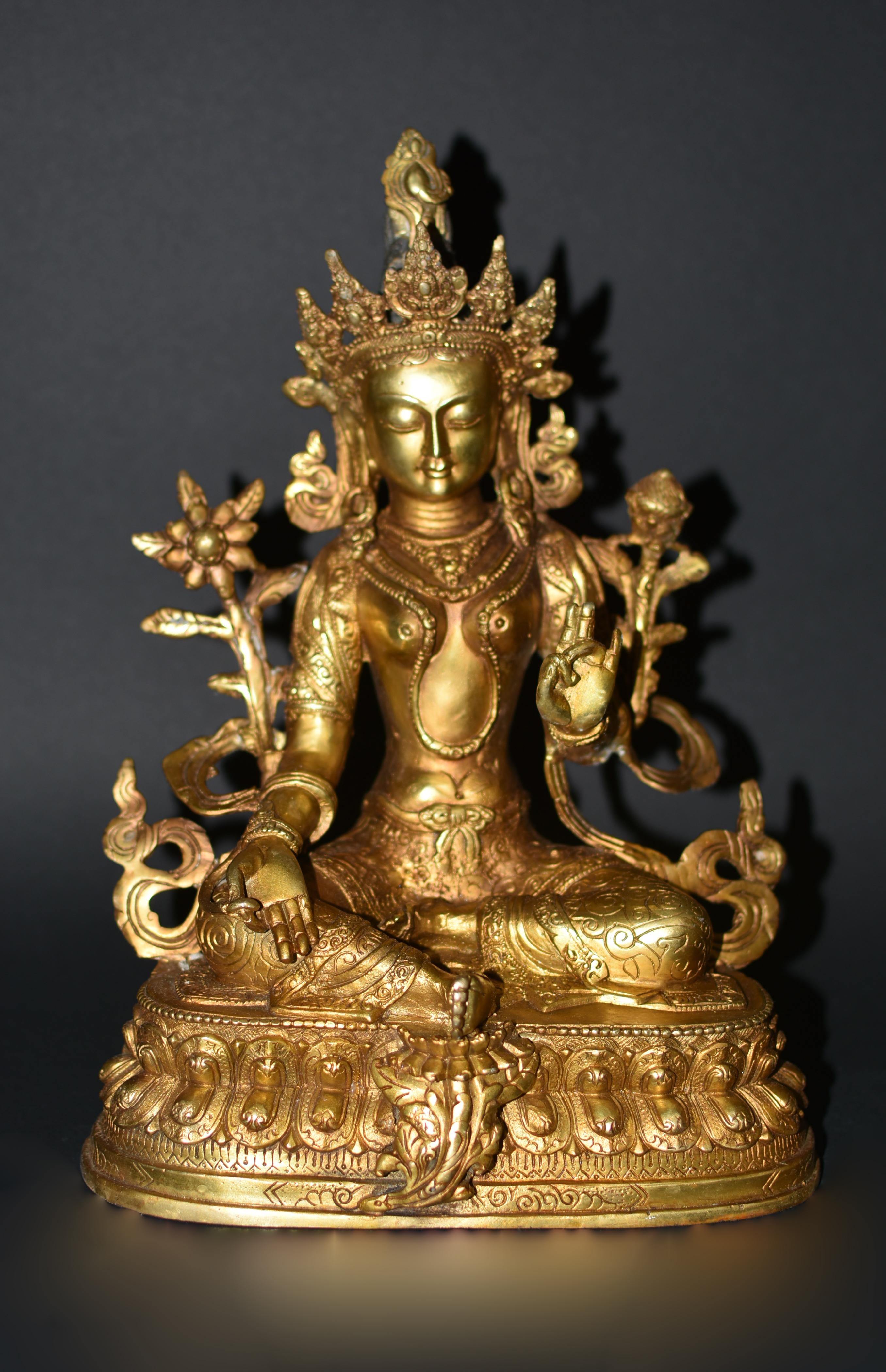A beautiful gilt bronze statue of Tibetan Green Tara. The Goddess is seated in lalitasana on an elaborately incised double-lotus base with the pendant foot resting on a smaller lotus, the right hand extended in varadamudra and the left held in