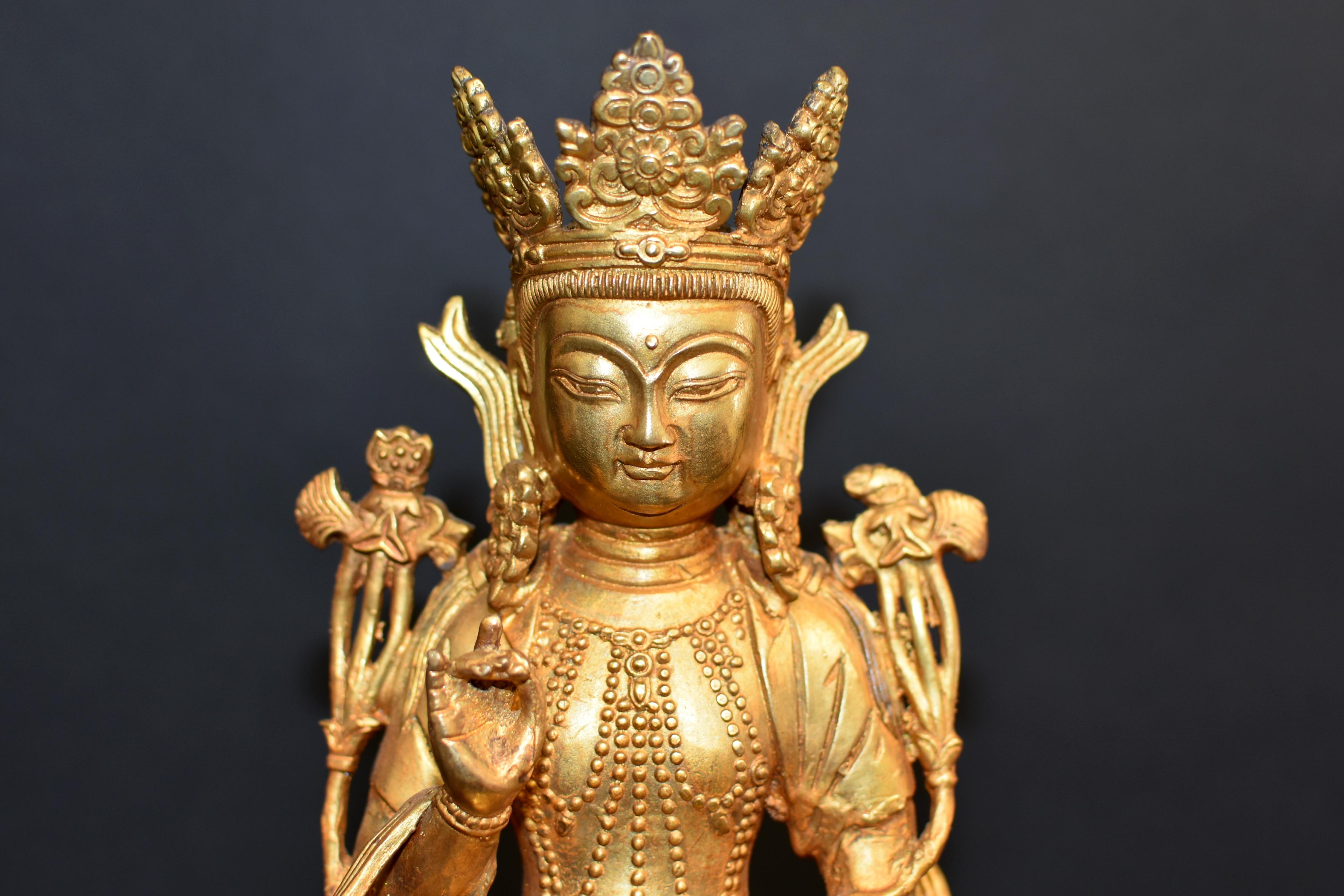 A beautiful 10 lb, gilt bronze statue of Tibetan White Tara. Seated in dhyanasana on a 4-tier lotus pedestal rising above holy beast on padmasana (single petal row lotus throne), both hands in Karana mudra to expel evils. Her small exquisite face