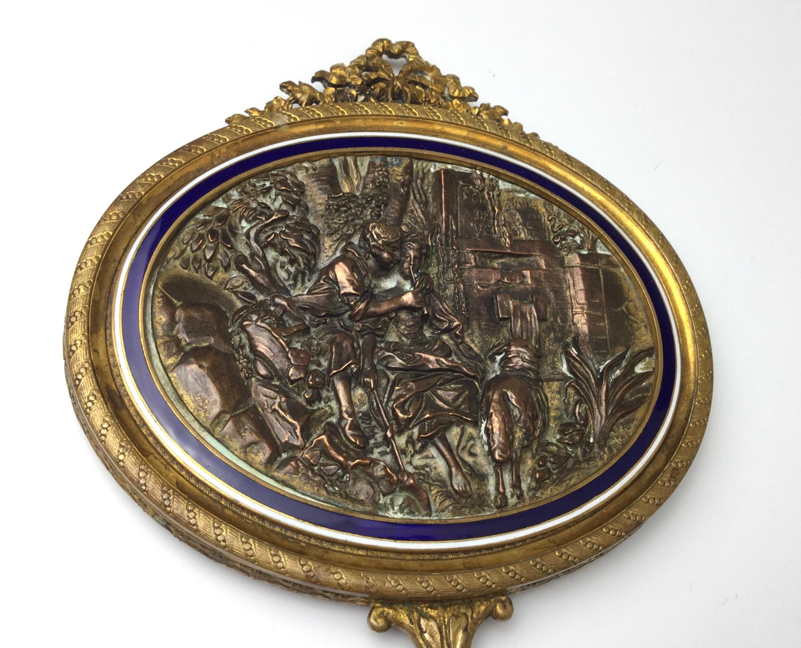 Wonderful gilt bronze with blue and white enamel hand mirror. Marked France on one side of the handle and New York on the other. Measures: 10” by 5 1/4” Age appropriate ware to frame. Beveled mirror has some discoloring around the edges.