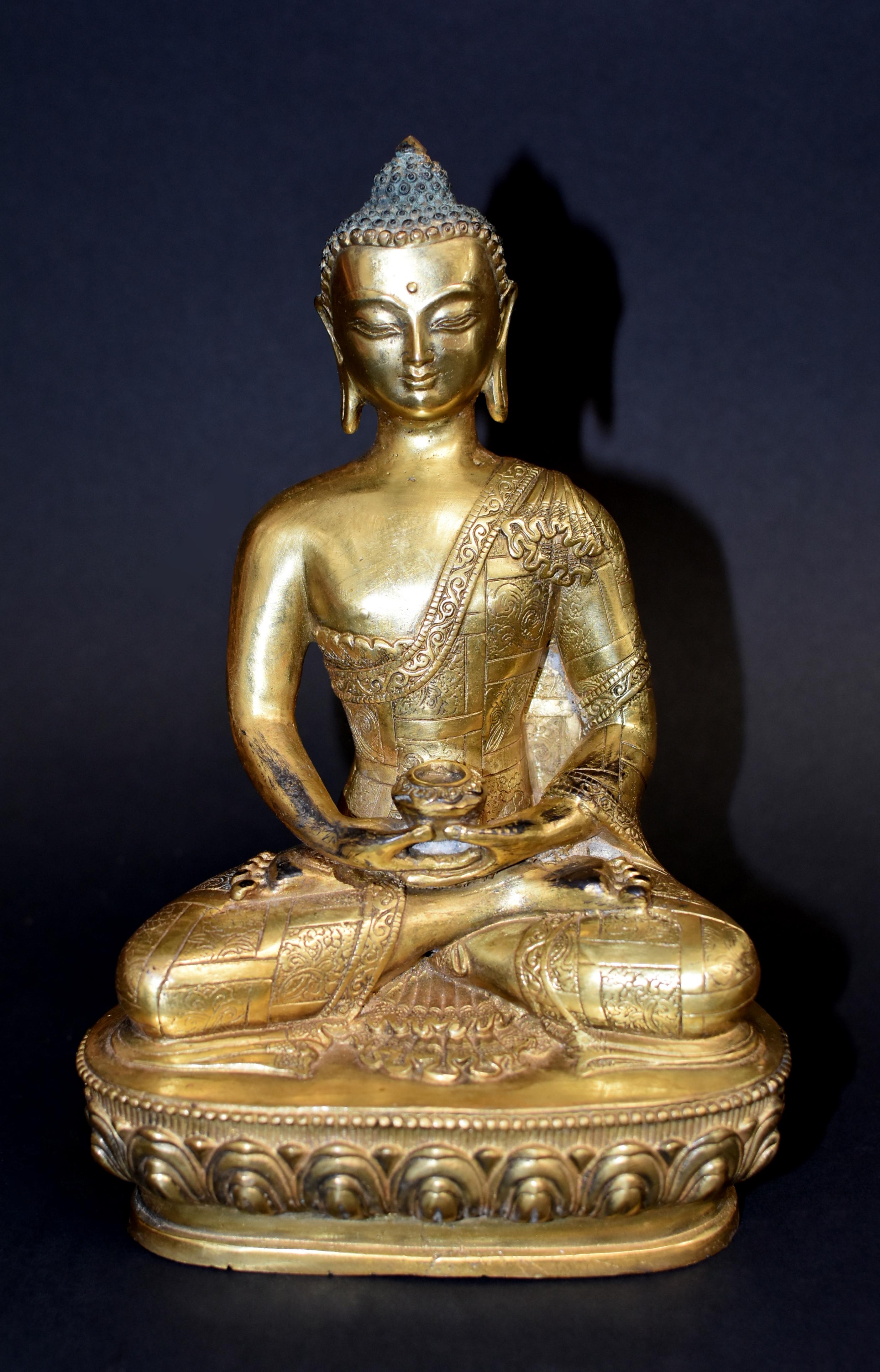 An exquisite gilt bronze statue depicting a young Sakyamuni Buddha. Seated in padmasana with the hands in dhyana mudra holding a bowl, his face serene with down cast eyes under high arched brows and a center ushinisha above pursed lips. Long