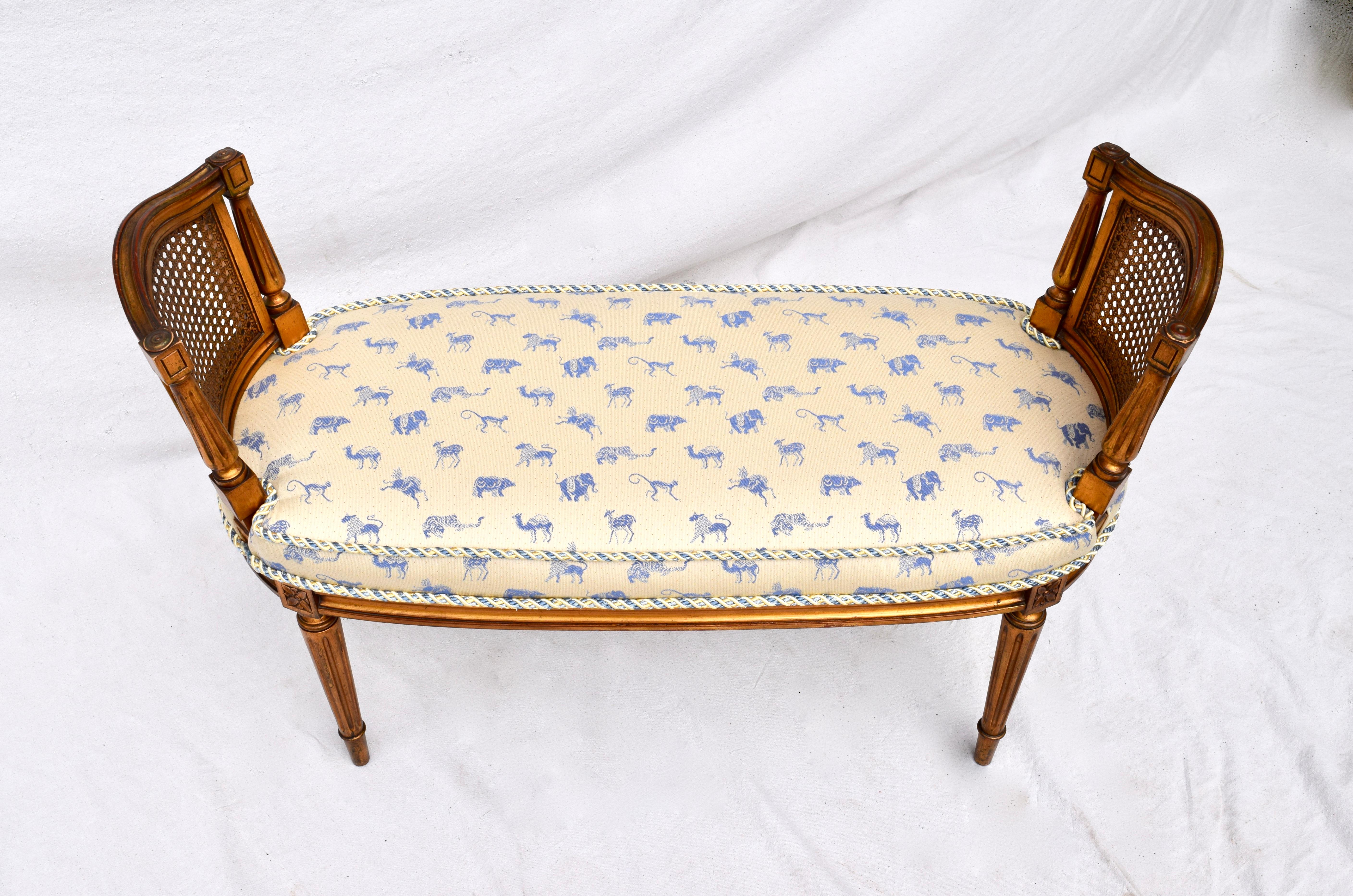 A decorative mid sized Louis XVI style cane and gilt window bench with attached cushion upholstered in exotic animals cotton fabric. Distinct features include curved caned sides and seat accented with complimenting thick rope cording. Lovely patina.