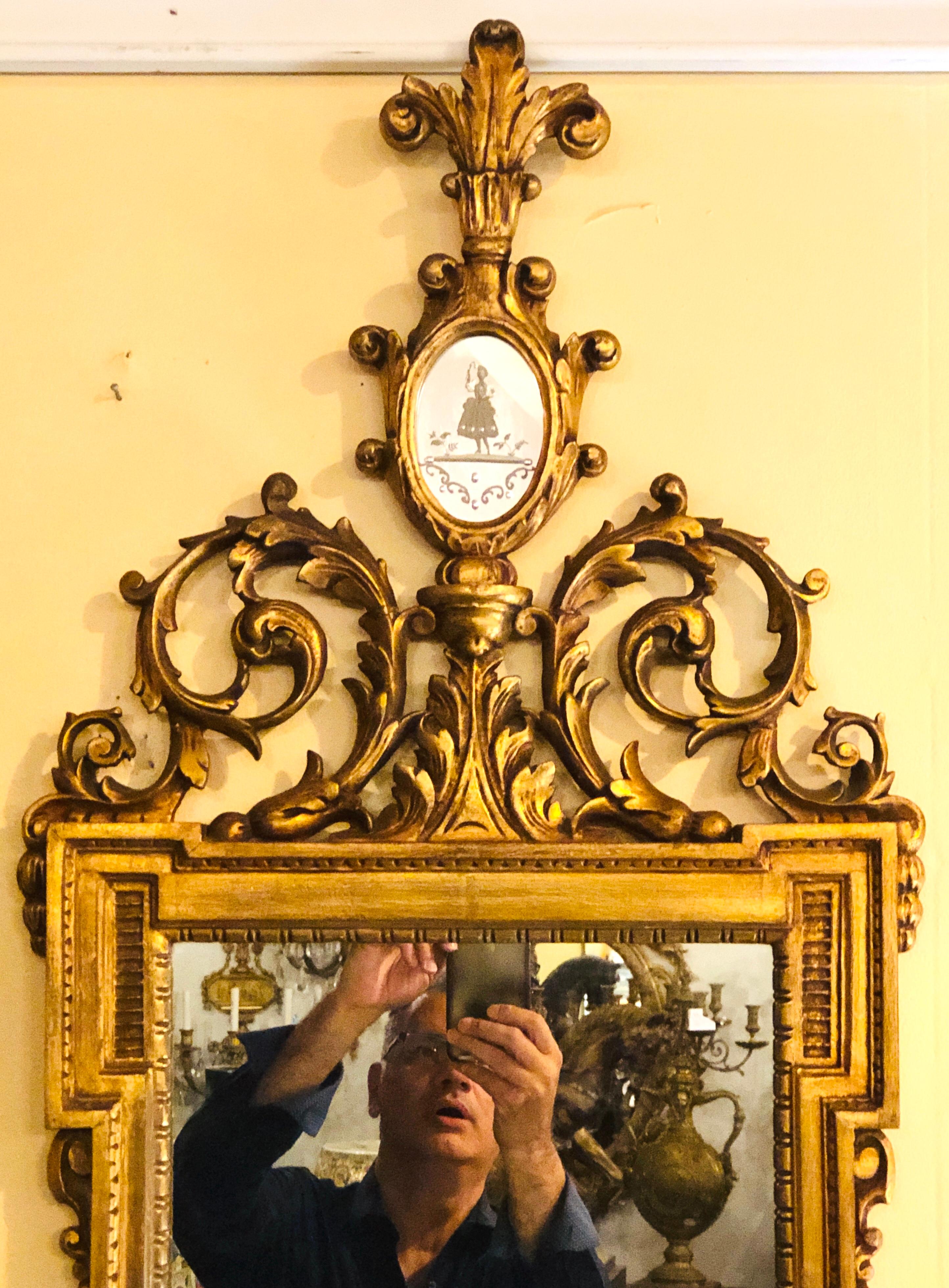 Vergoldeter, geschnitzter Spiegel mit hohem, offenem Fleur-de-Lis-Giebel und ovalem, geätztem Spiegelfeld einer jungen Dame in voller Montur.