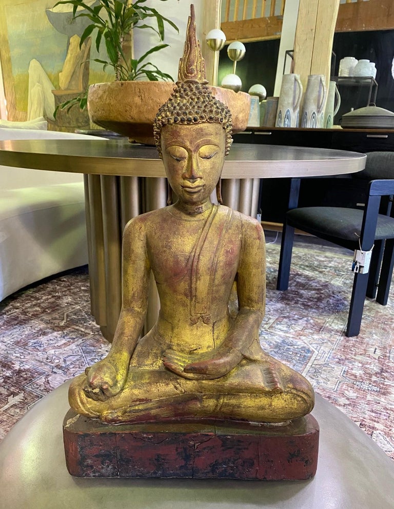 A finely carved and detailed seated wood temple shrine Buddha. Likely Northern Thai or lower Burmese. 

This particular Buddha has a wonderful serene expression. He sits cross-legged in the Padmasana or lotus pose and the offering in his hand is