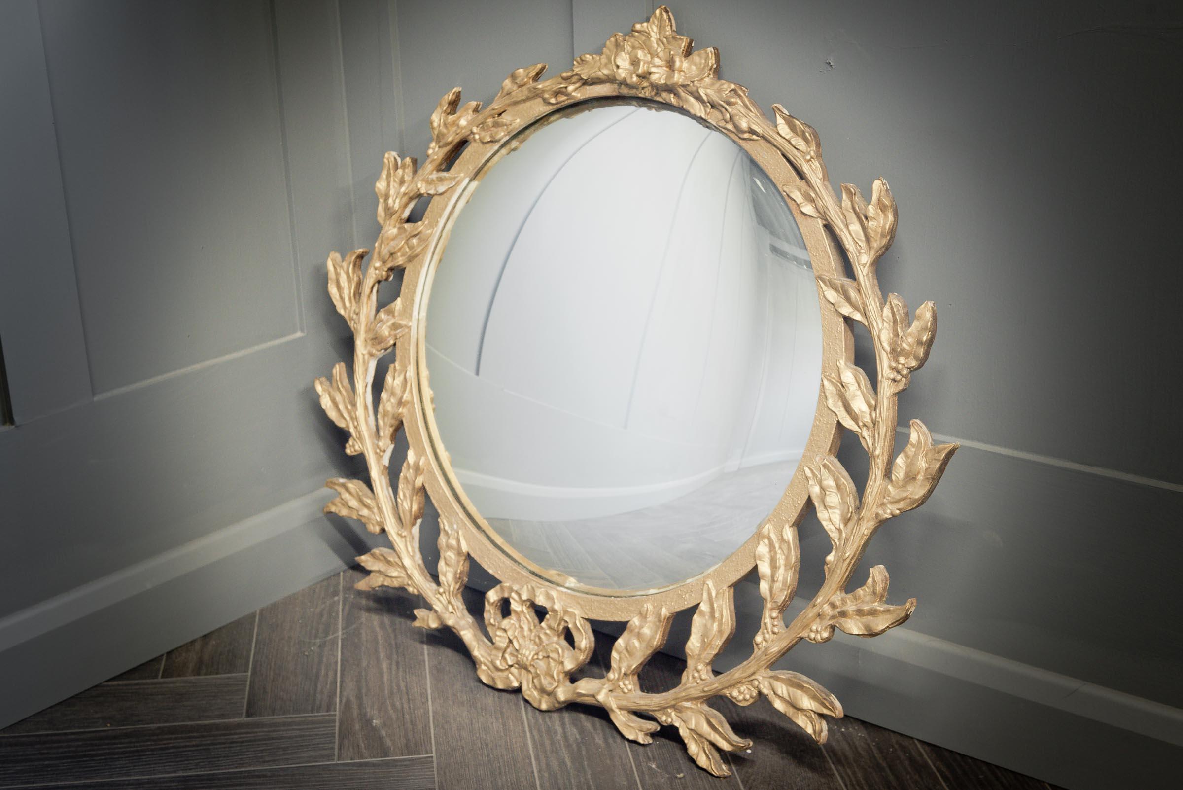 This beautifully detailed gilt over carved wood convex mirror has incredible laurel detailing. Perfect in any hallway or on any mantle, this will add character and elegance to your space.