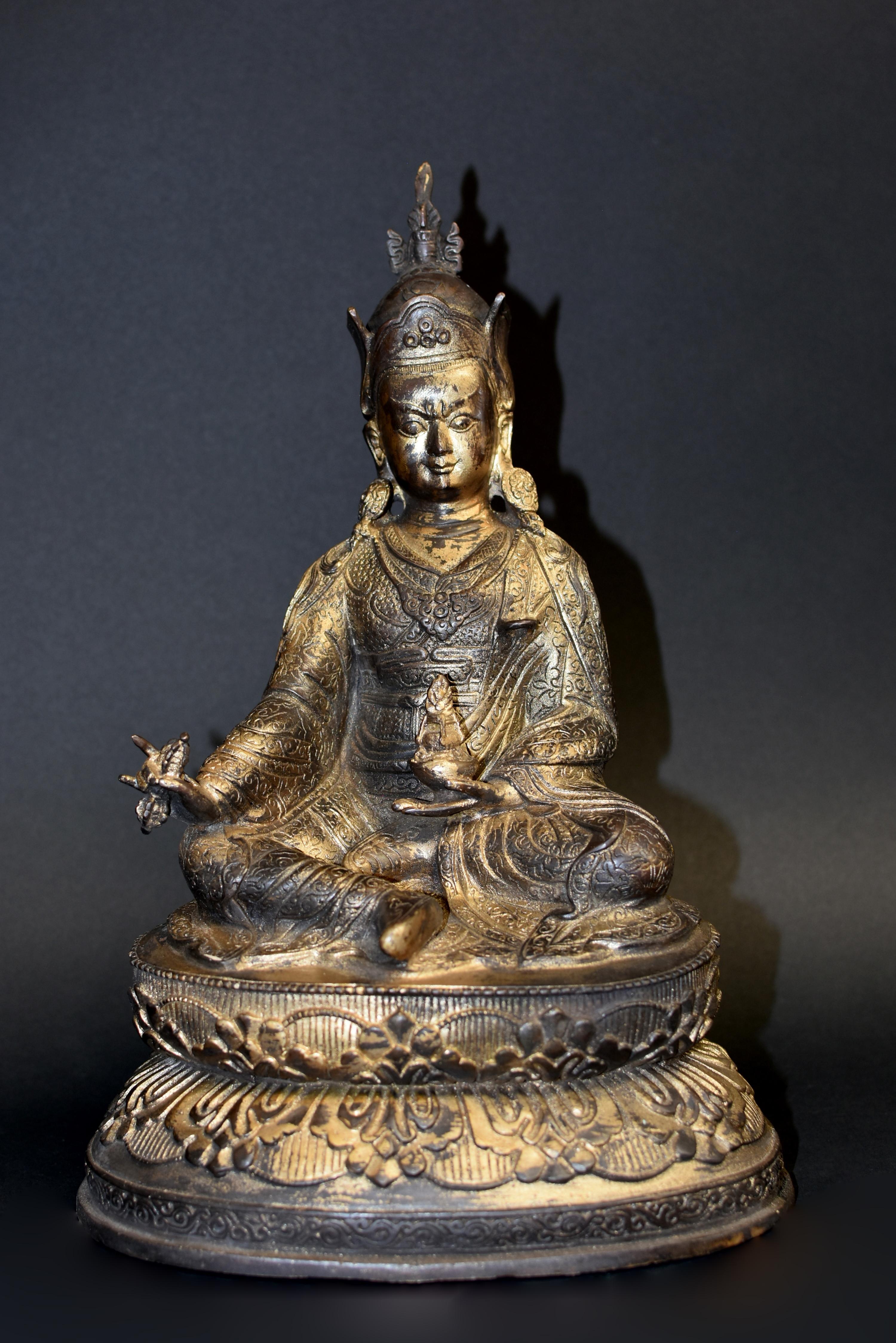 A wonderful 6.7 lb gilt copper statue of the great teacher, Padmasambhava, also called Guru Rinpoche. He is considered the founder of Tibetan Buddhism's oldest school. Seated on double lotus throne, he is wearing a peaked crown with upturned ear