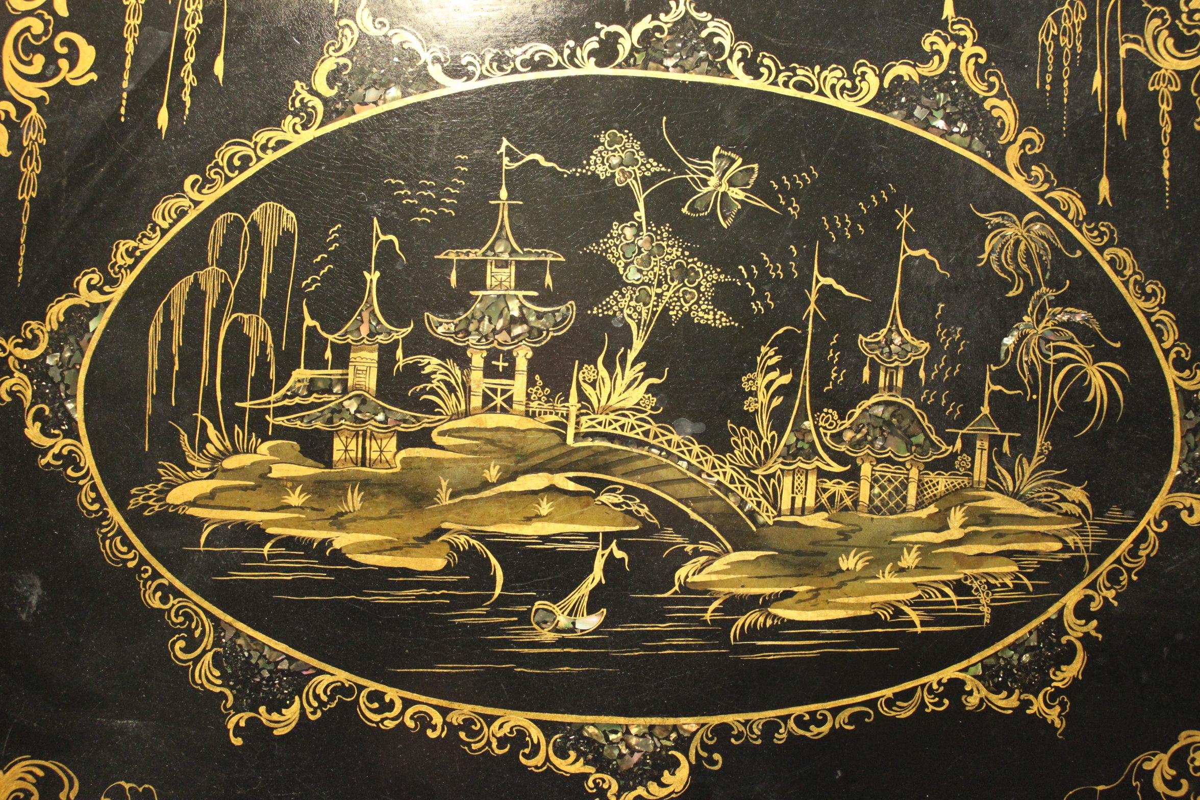 This very decorative and striking Queen gothic papier mache tray is decorated with inlaid abalone shell and a fantastic gilt chinoiserie scene to the central cartouche which itself is surrounded by C-scrolls, stylised flowers and pendant foliage. It