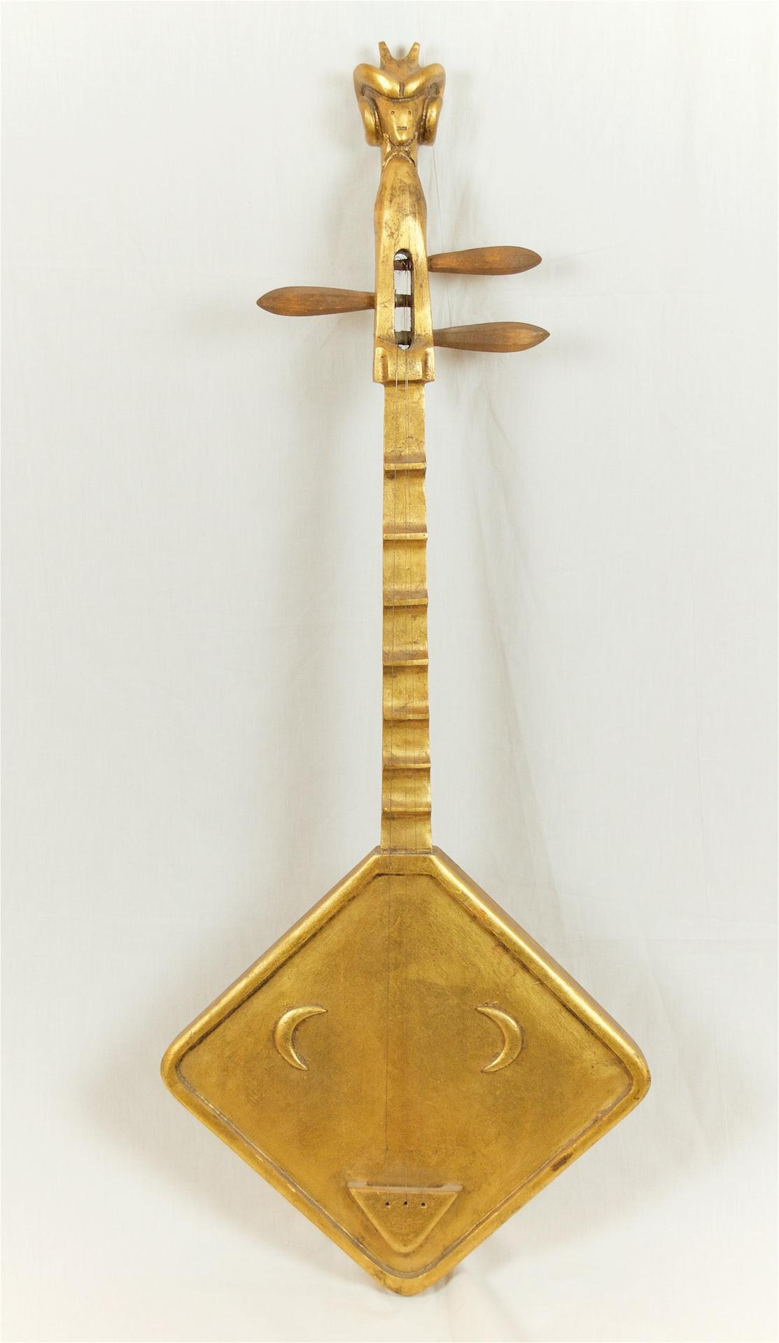 Decorative musical instrument in carved wood with gilt finish, featuring strings, turnings and a carved animal's face at the headstock. Whimsical accent piece can be hung with a single triangle hook on back.