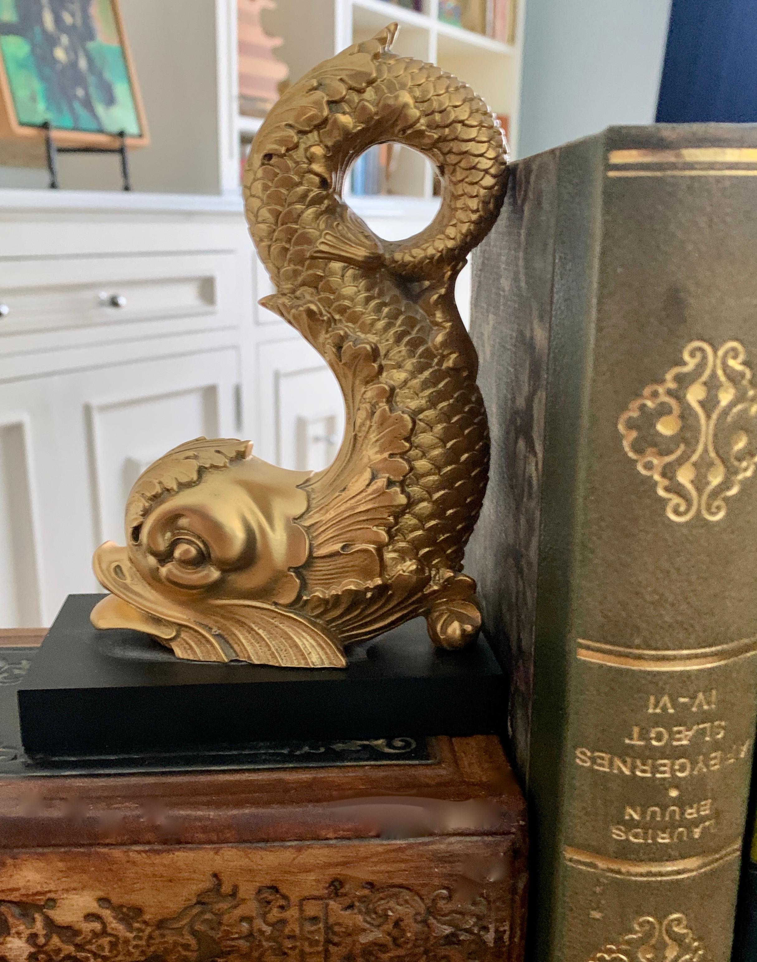 Gilded metal dolphin bookend on marble base, a very detailed form perfectly suited as a paper weight, sculpture or bookend in many rooms. Decorative as a stand alone piece or practical on the desk top or den.