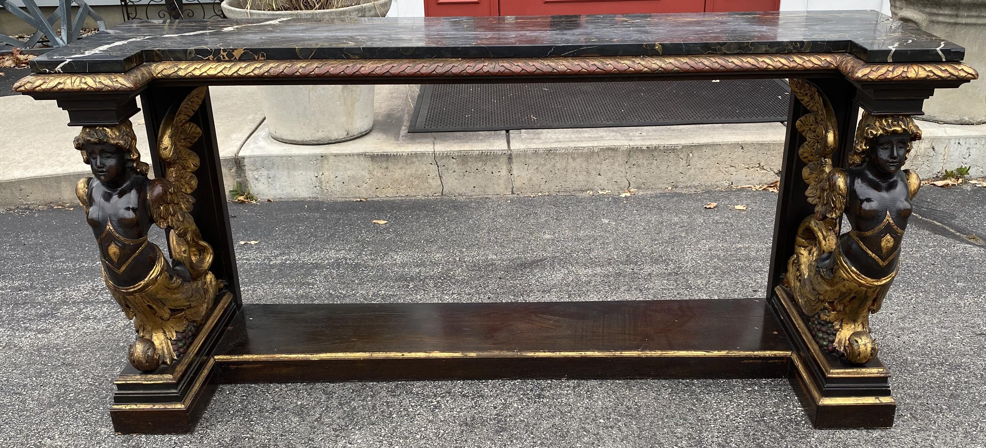 A splendid gilt and ebonized pier table, probably oak, with custom marble top, berry 
scroll decoration and winged caryatid supports. The piece is probably Italian in origin, starting as a base for a larger cabinet, and most likely dates to the