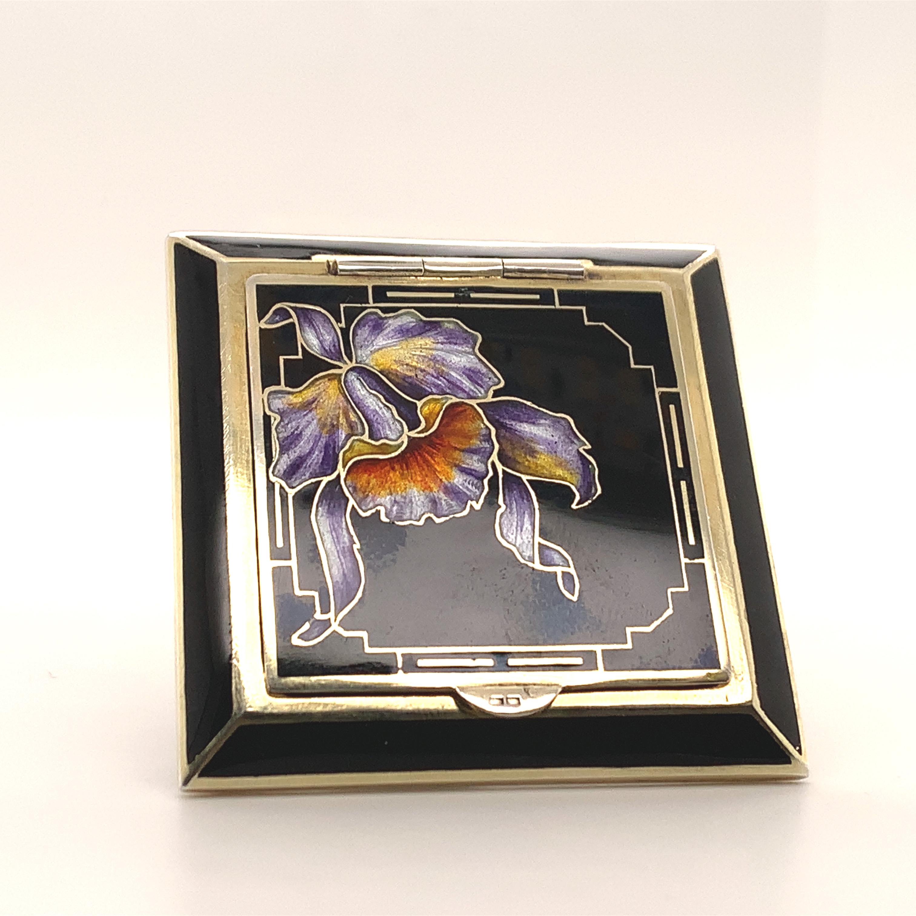 Striking and beautiful hinged compact.  Black enamel with a luminous enamel iris outlined in gold leaf.  Inside, there is a mirror and a reticulated sifter that spins to open.  Gilt metal.  Unique square shape.  2 1/8