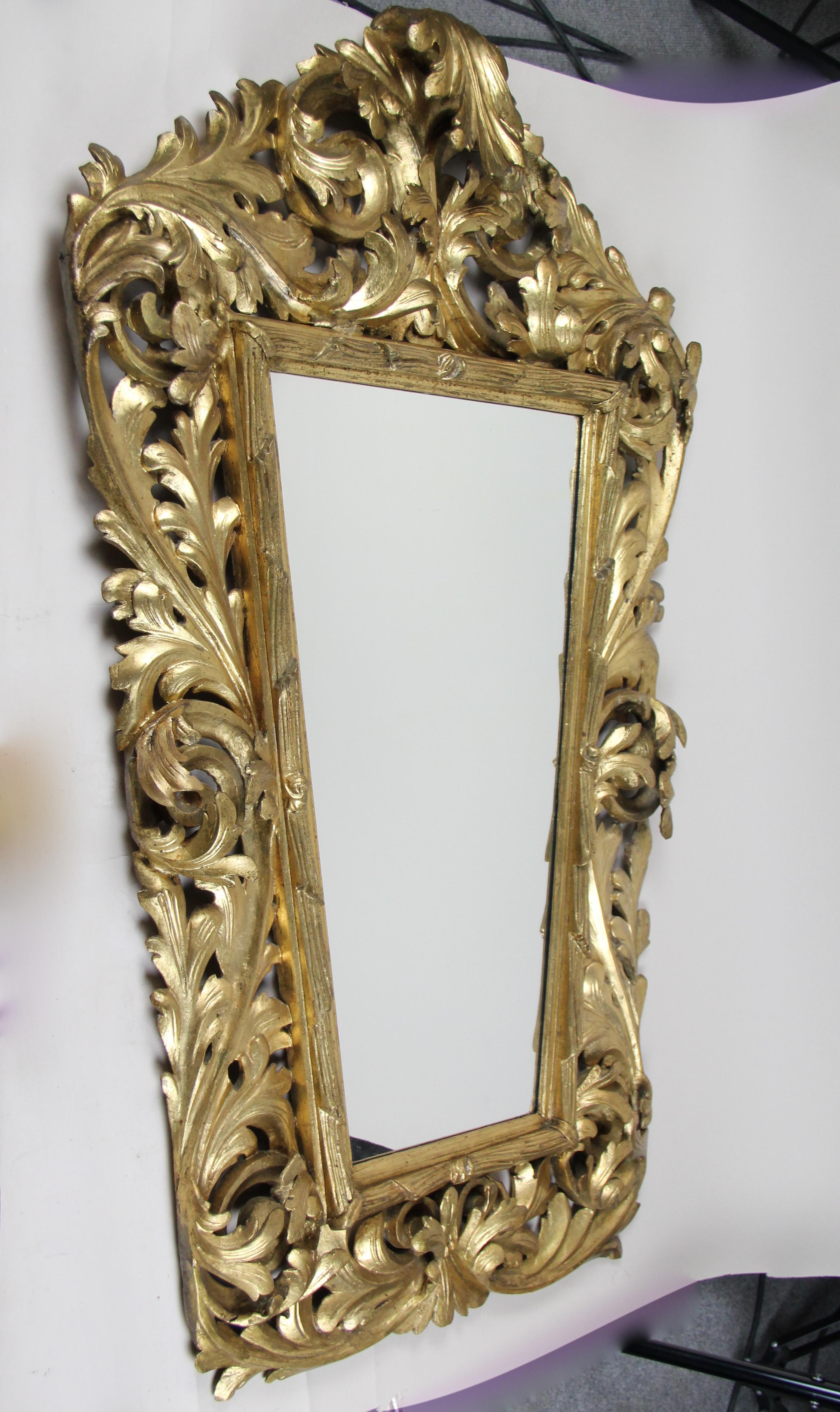 Majestic hand carved gilt Florentine wall mirror from Austria dating back to the mid-19th century, circa 1850. The massive basswood frame is ornamented by elaborately hand carved acanthus leaf motifs. Unique shaped lines in combination with an