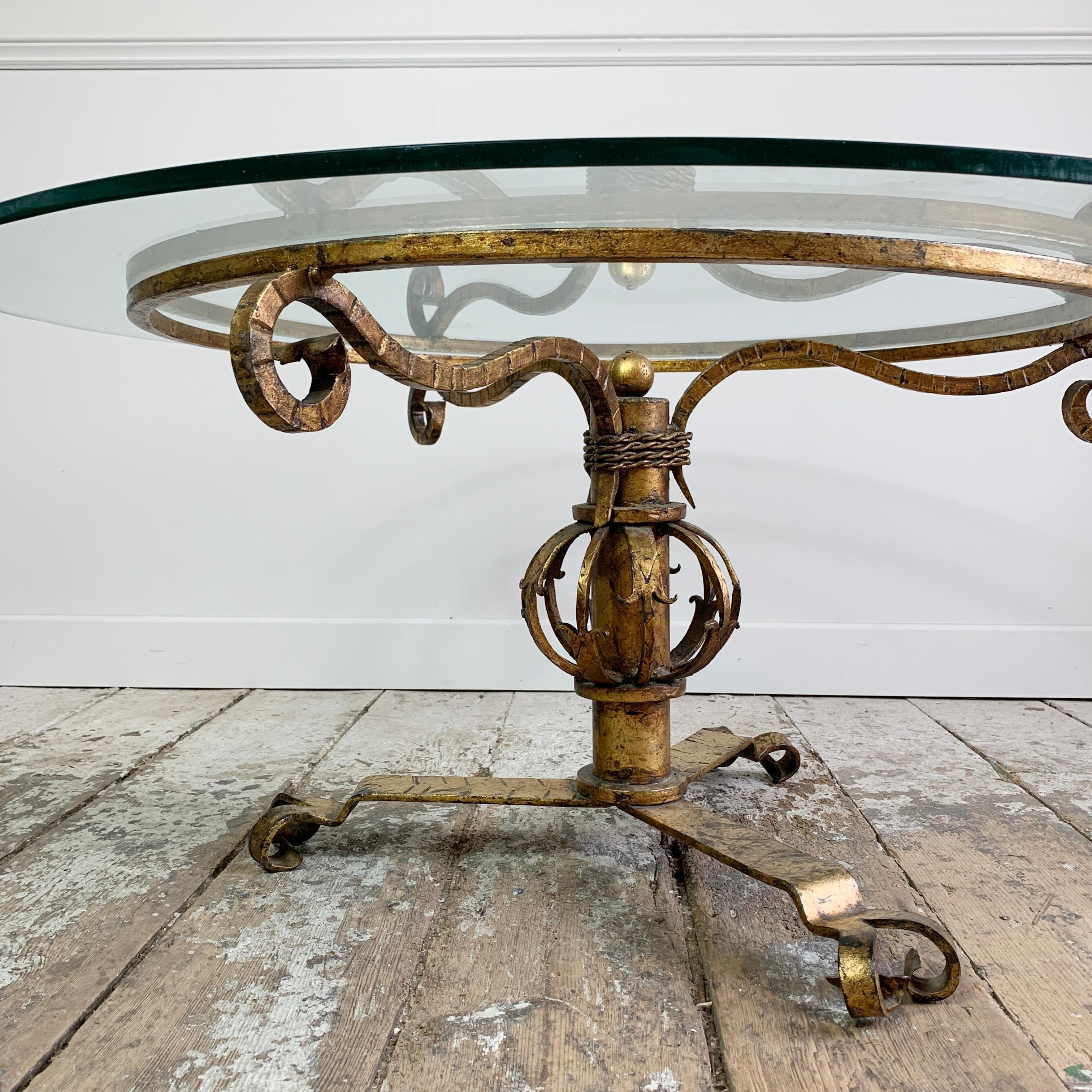 Superb 1930's gilt Spanish coffee table. Intricately hand forged in Iron, the table is wonderfully decorative, with rope twist, and turned details.

The worked iron has been completely gilded, and the top is a replacement glass.

Measures: Width