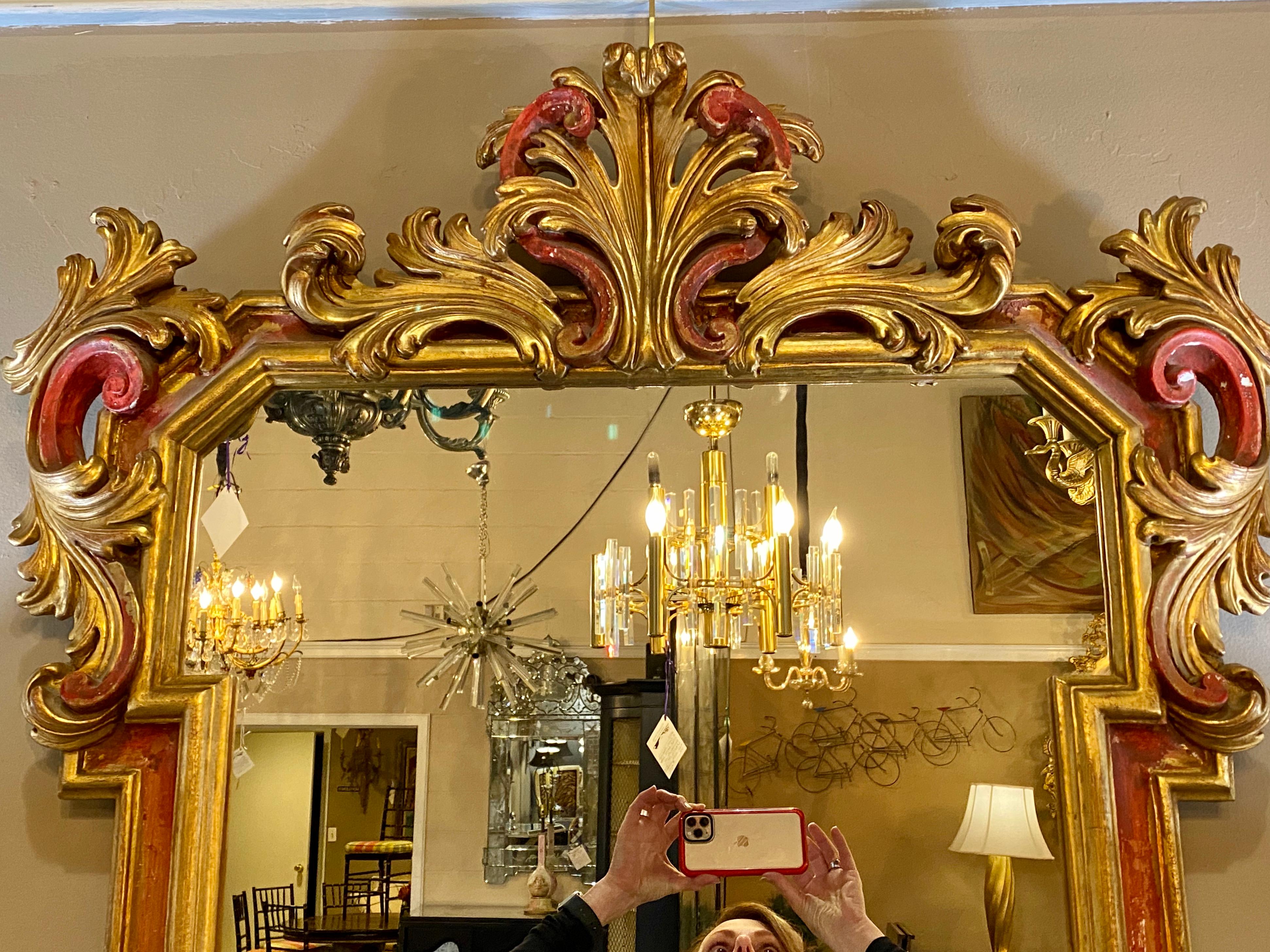 A very fine wooden mirror with red paint decorated undertones on gold gilt hi lights. Nice geometric frame with a gilt floral leaf design border.
