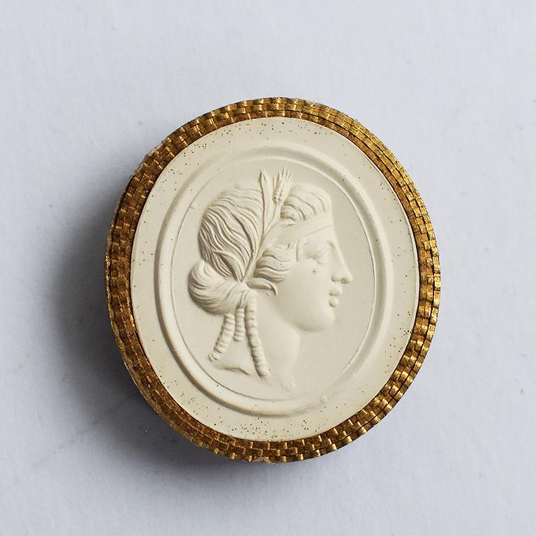 This is a 19th century Intaglio Tassie - A seal with the head of Proserpina or Proserpine on it. Thick gilt paper wrapped around the edge mimicking a frame.
There are a few tiny faults in the mold but no damage. Has the number 153 penciled on the
