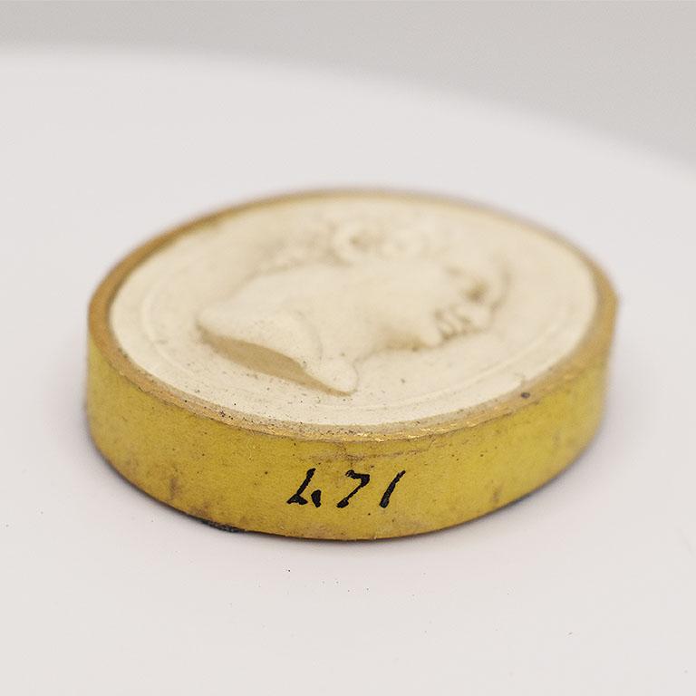 This is a 19th-century Intaglio Tassie - A seal with the bust of a man on it. Thick gilt paper wrapped around the edge mimicking a frame. There are a few tiny faults in the mold but no damage. The number 471 is penciled on the side, as this was part