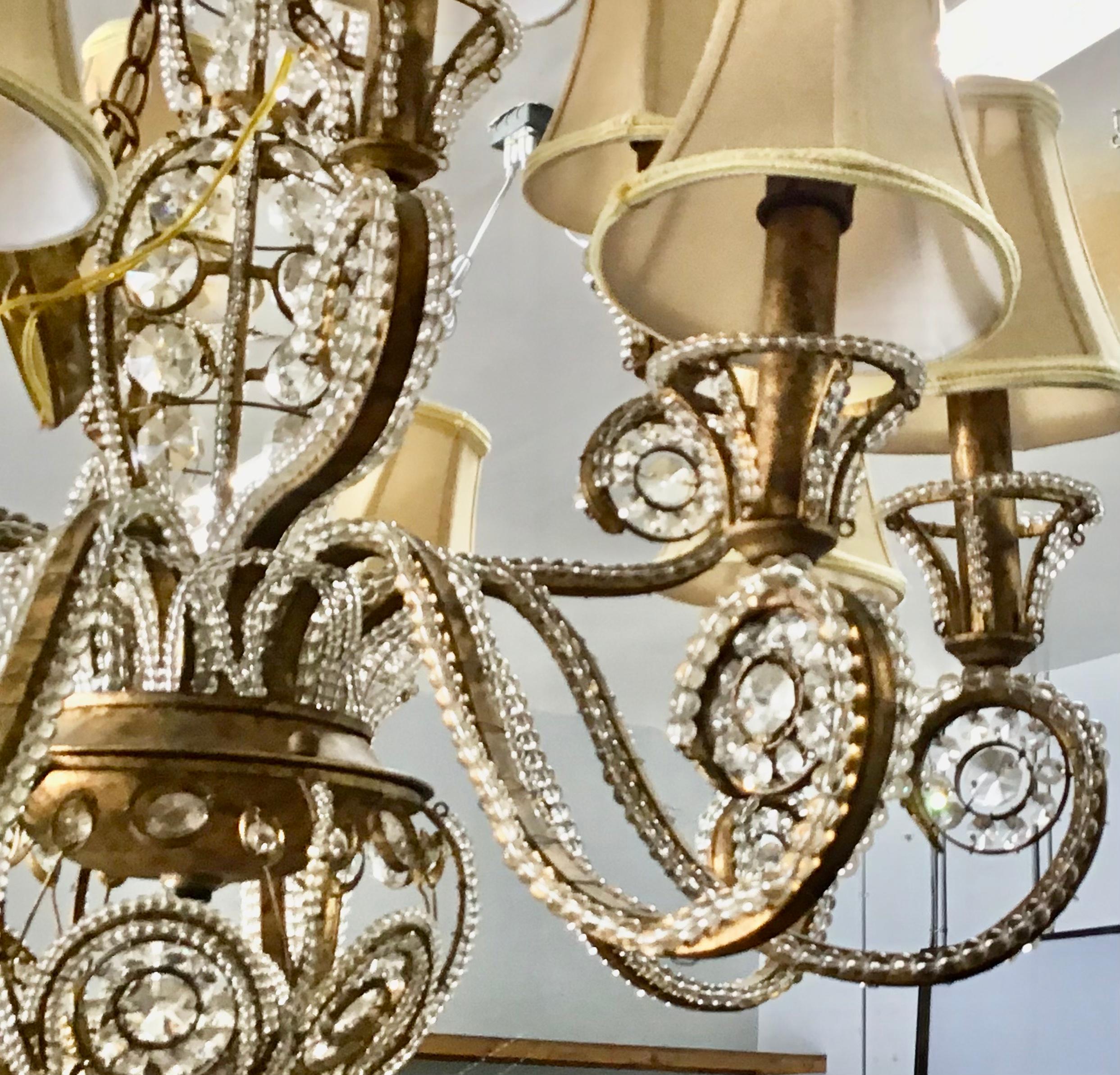 Beautiful, gilt-iron and crystal beaded chandelier. The chandelier consists of a scrolled iron frame with a gilt finish. A bounty of crystal prisms and bead garlands complete the look. Measures: 35 inches with a 16 inch chain. 
The chandelier is