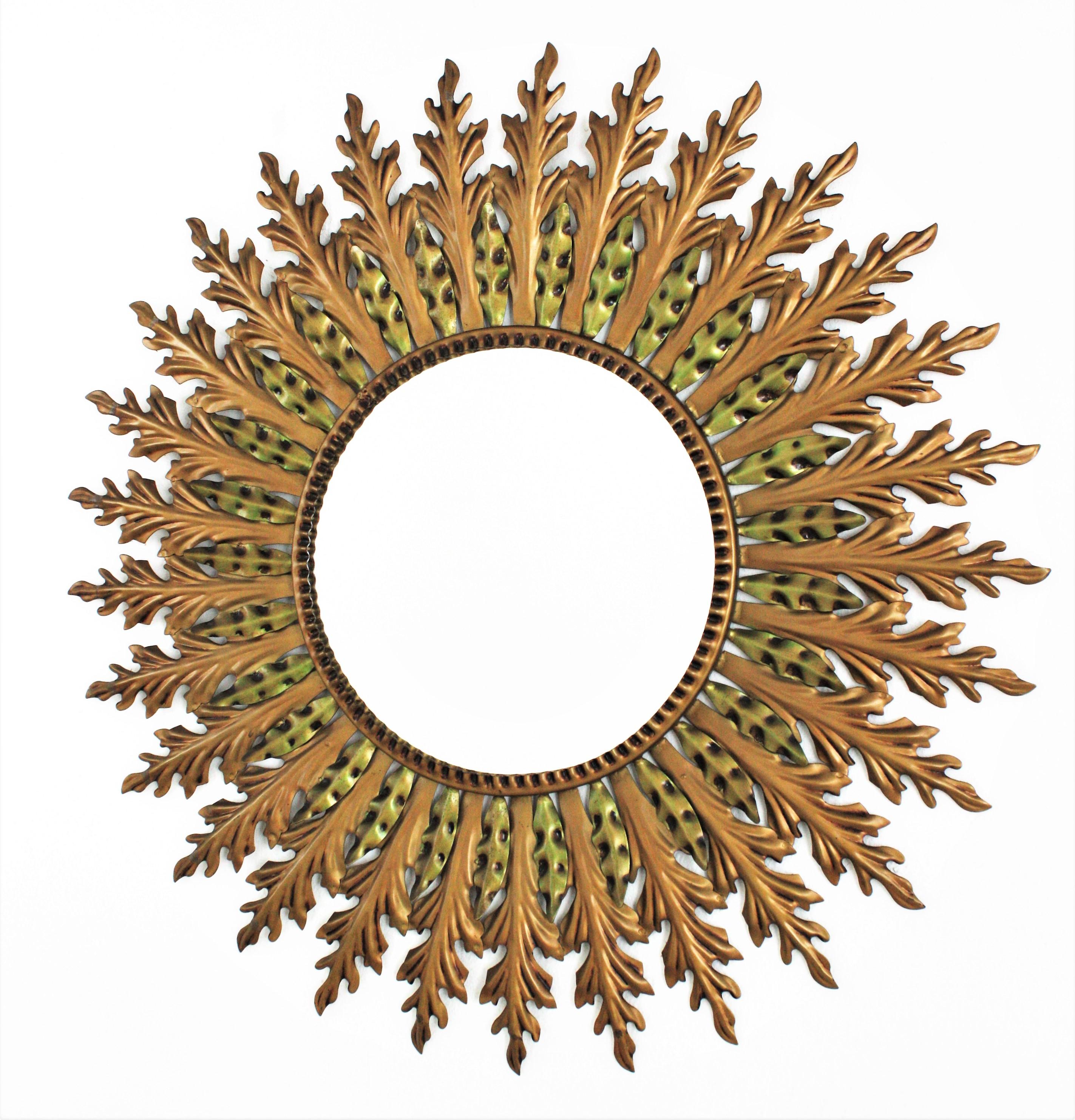 Eye-catching Hollywood Regency gilt metal and green double layered sunburst mirror, Spain, 1960s.
This sunburst wall mirror has a layer of gilt iron large leaves and a layer of small green patinated leaves.
This wall mirror will add a glamorous