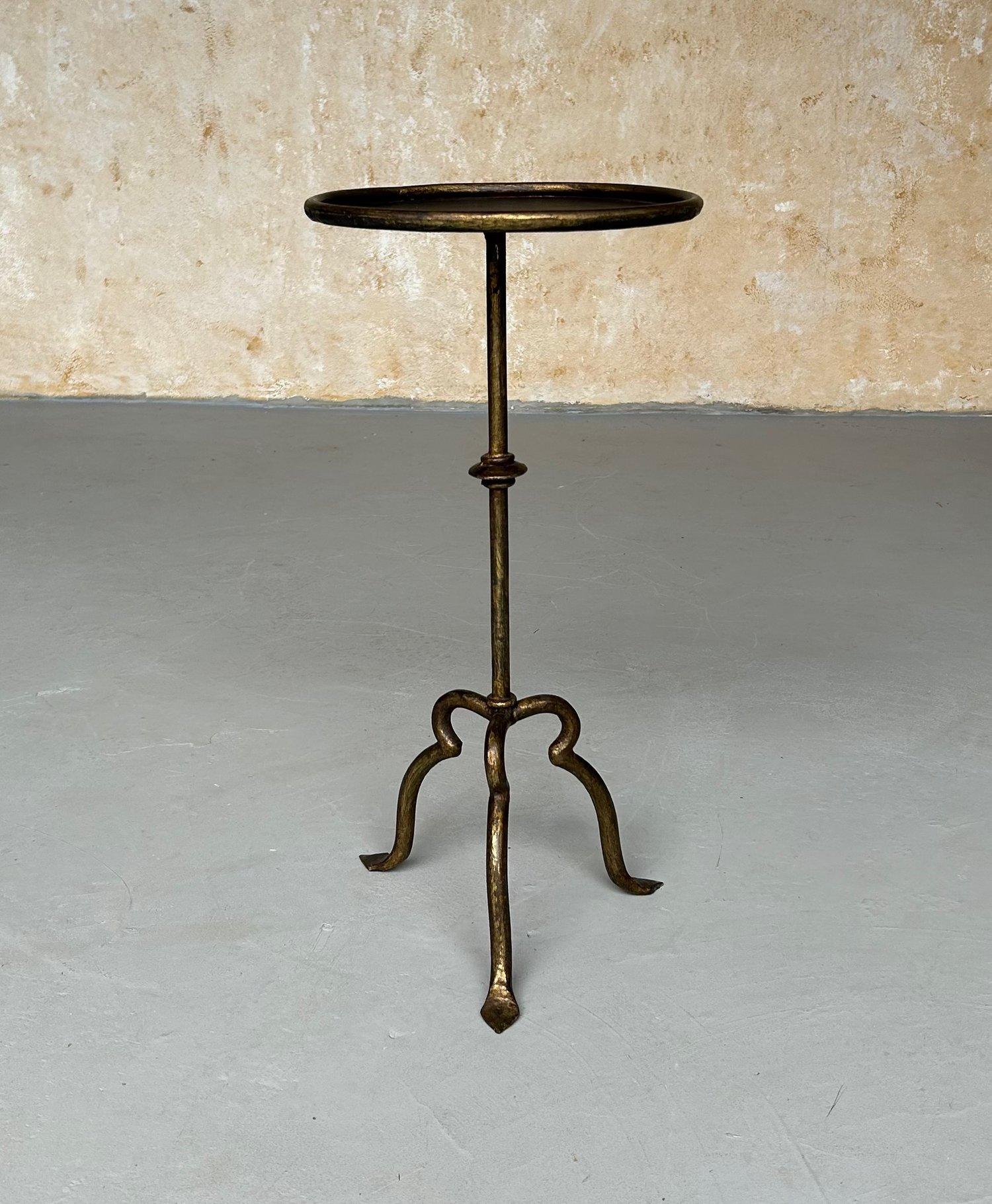 A unique, vintage-inspired side table, recently hand-crafted by European artisans. Its small-scaled design features a hand-applied gold patina and a whimsical, elevated tripod base with upward-scrolled feet, making it ideal for drinks, coffee, or