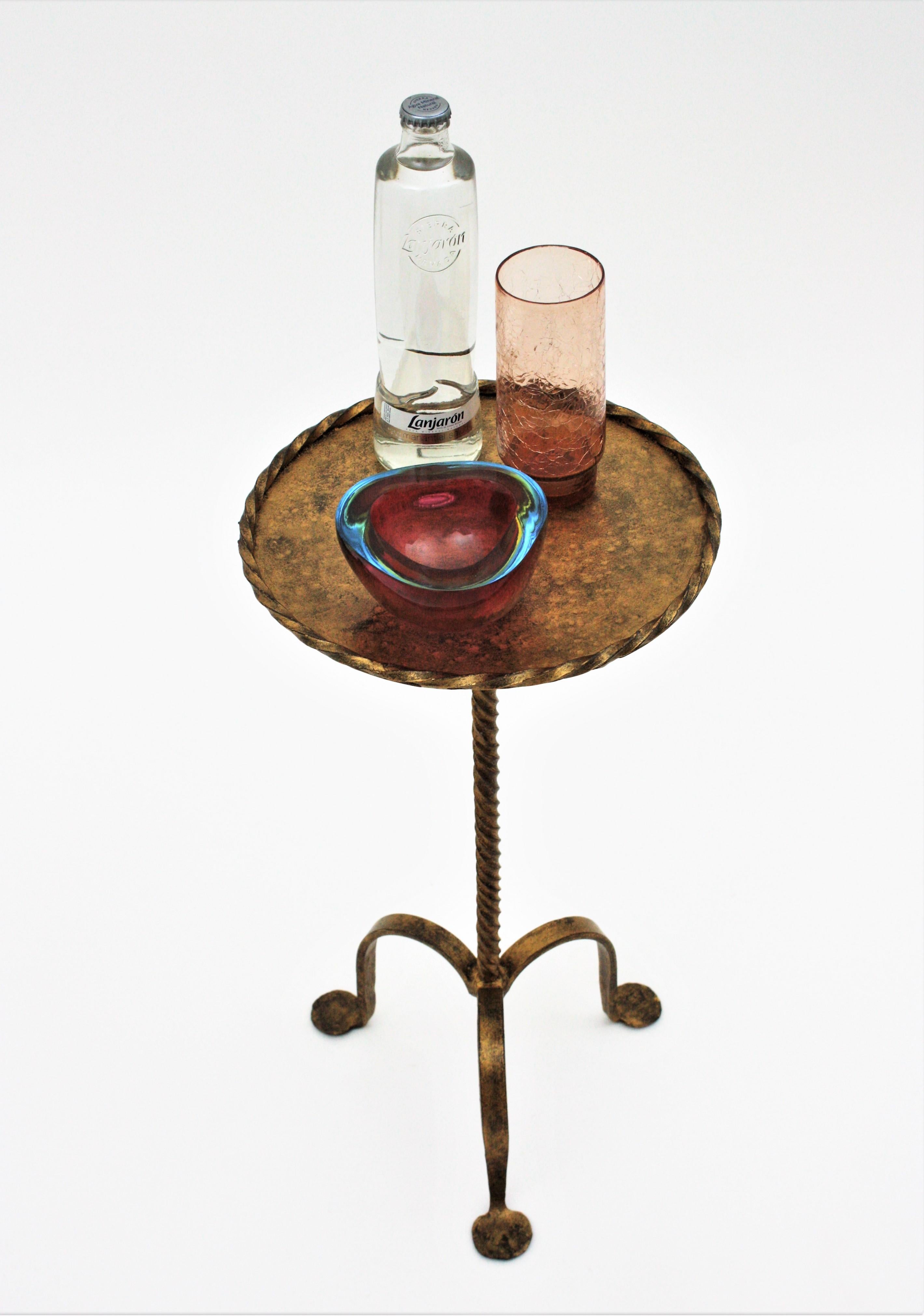 Gothic style hand-hammered gilt iron guéridon or pedestal table with twisted edged top standing on a tripod base, Spain, 1930s.
This Martini table stands on a three-footed baseand it has a richly twisted stem. The top has a twisted iron rope