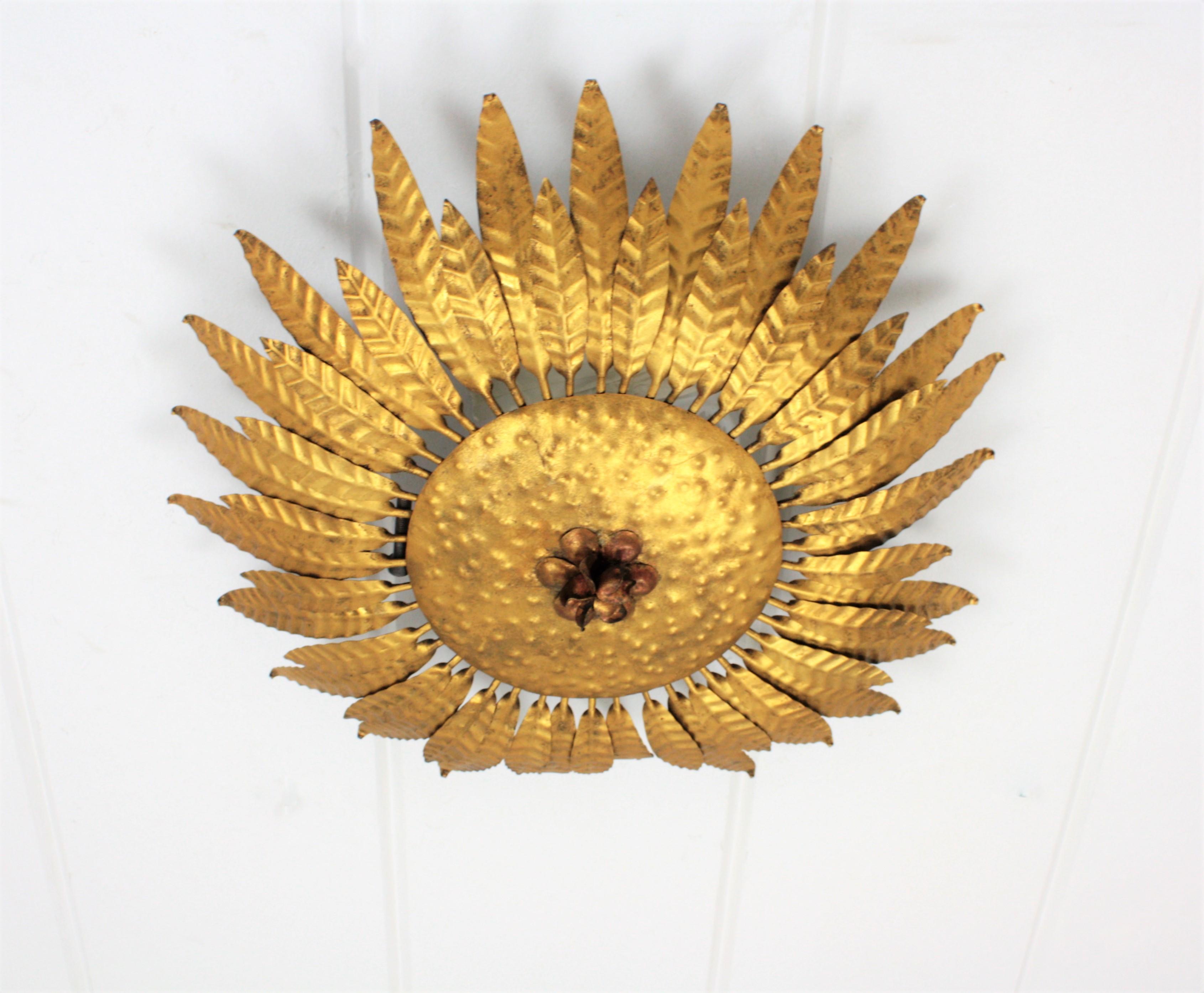 Eyecatching handcrafted gilt iron flower burst ceiling sconce or wall light fixture. Spain, 1960s.
It has a beautiful frame with leaves and a red flower accenting  the center of the fixture. 
Manufactured in Spain at the Mid-Century Modern Period in