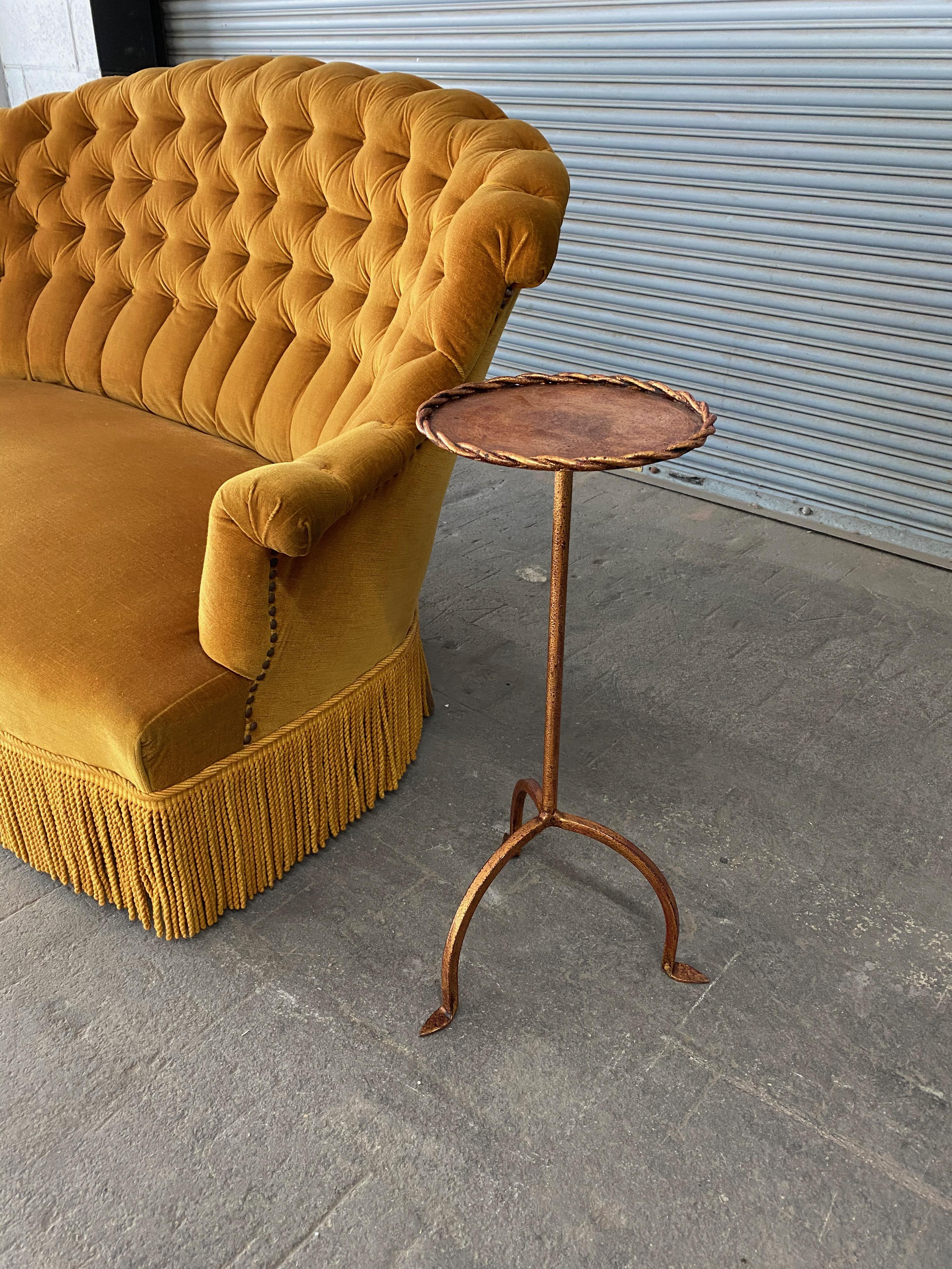 A gilt iron and metal end table on tripod base and the top is framed in with a twisted braiding. This small side table has the original hand applied gold finish with black and Venetian red undertones, creating a rich and unique finish. We do have