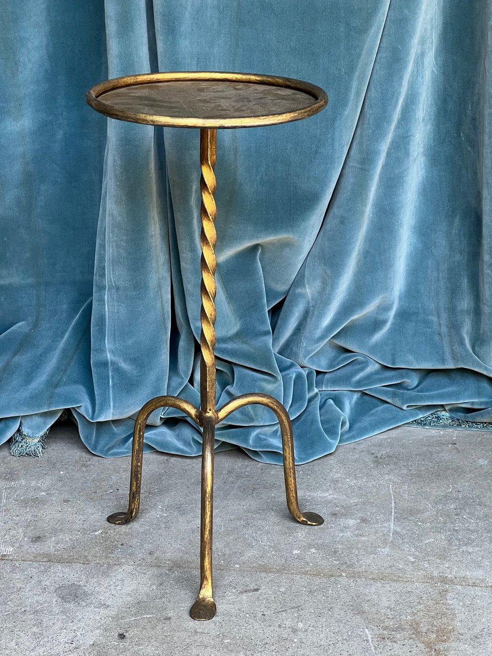 A handsome Spanish gilt iron drinks table from the 1950s, a unique and charming piece that will surely catch the eye. This small side table features a twisted stem design mounted on a sturdy tripod base, creating an aesthetically pleasing