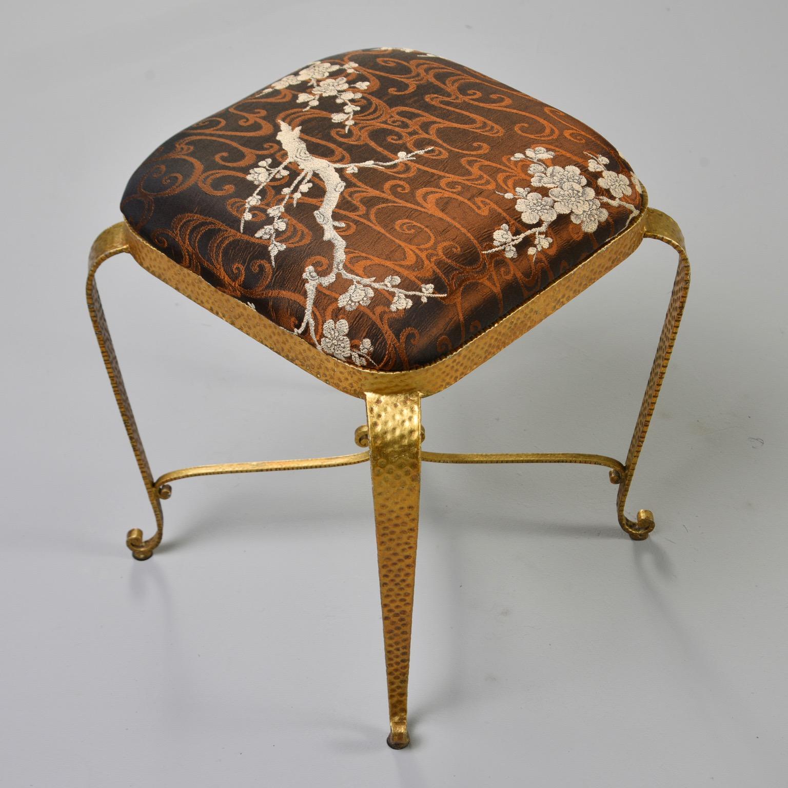 Italian gilt iron frame stool features a hammered surface texture, X-form stretcher with scrolled top, curved feet and upholstered seat in a bronze colored Asian brocade, circa 1960s. Unknown maker. Sold and priced individually. Two stools available