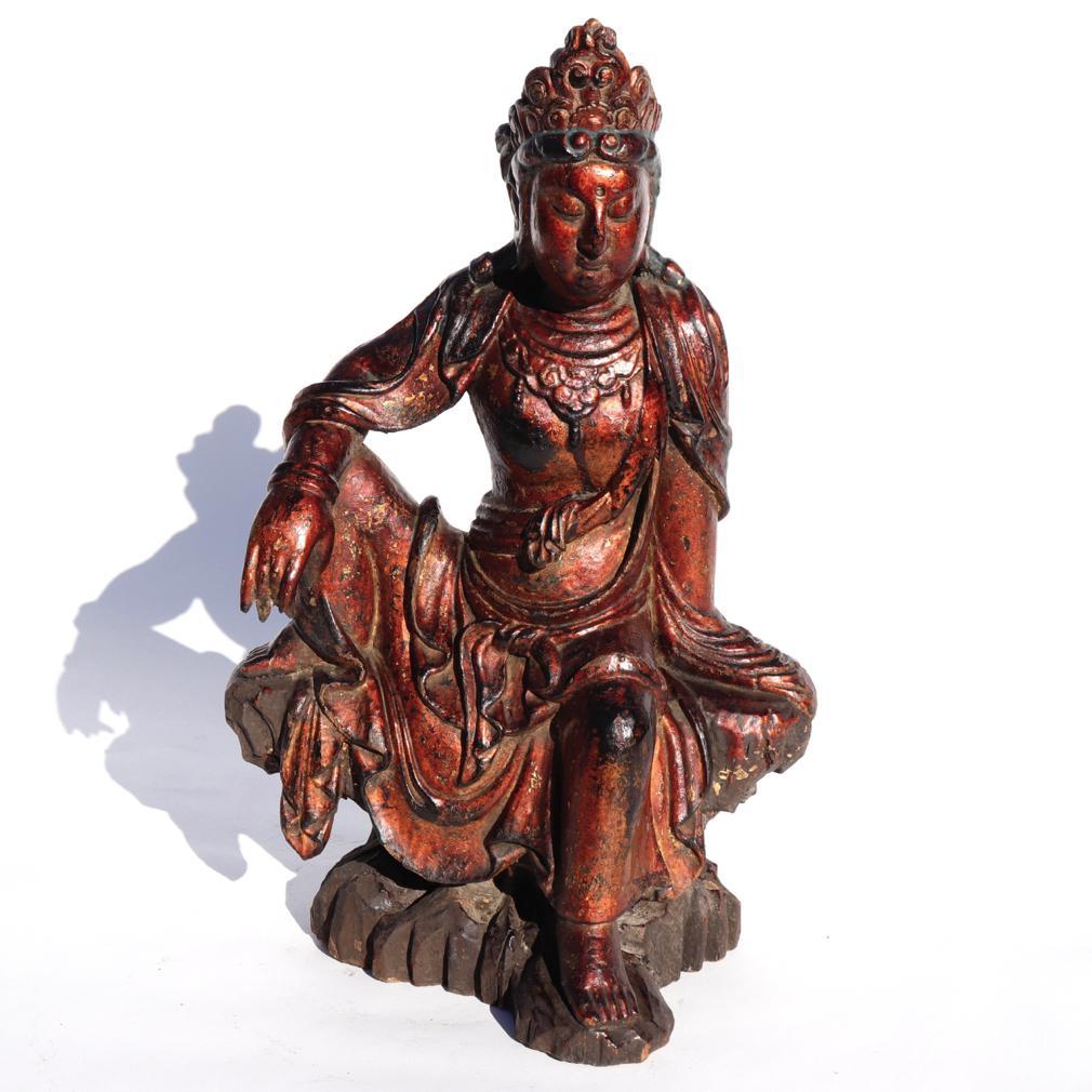 The Bodhisattva of Compassion (Avalokitesvara) seated majestically in rajalilasana, the position of royal ease, with the right forearm resting on the knee of the raised right leg, while the left leg dangles forward. The left hand supports the pose,