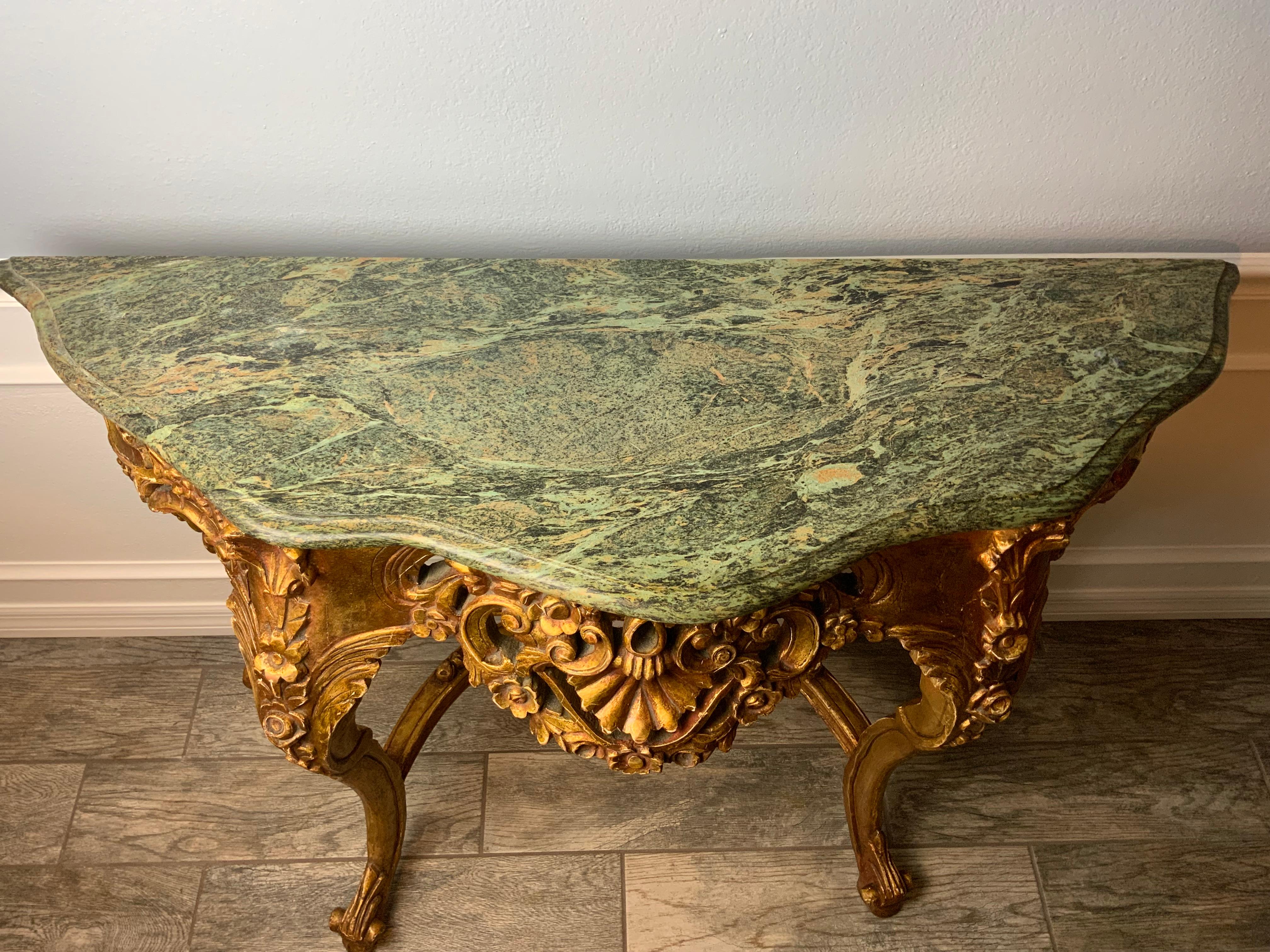 A very nice carved gilt console table probably from the early to mid-20th century. Great patina and color to the old surface. Beautiful Marble top with a molded ogee edge with different shades of greens and gold.