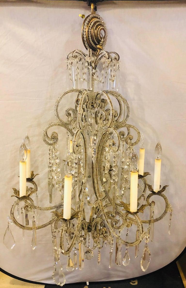 Fine Beaded and Crystal Venetian Style Chandelier
Gilt metal 8-light crystal frame beaded with hanging crystal prisms, this 1950s chandelier is simplistic enough to hang in any setting. The scroll metal swag and circular form arms are all covered in