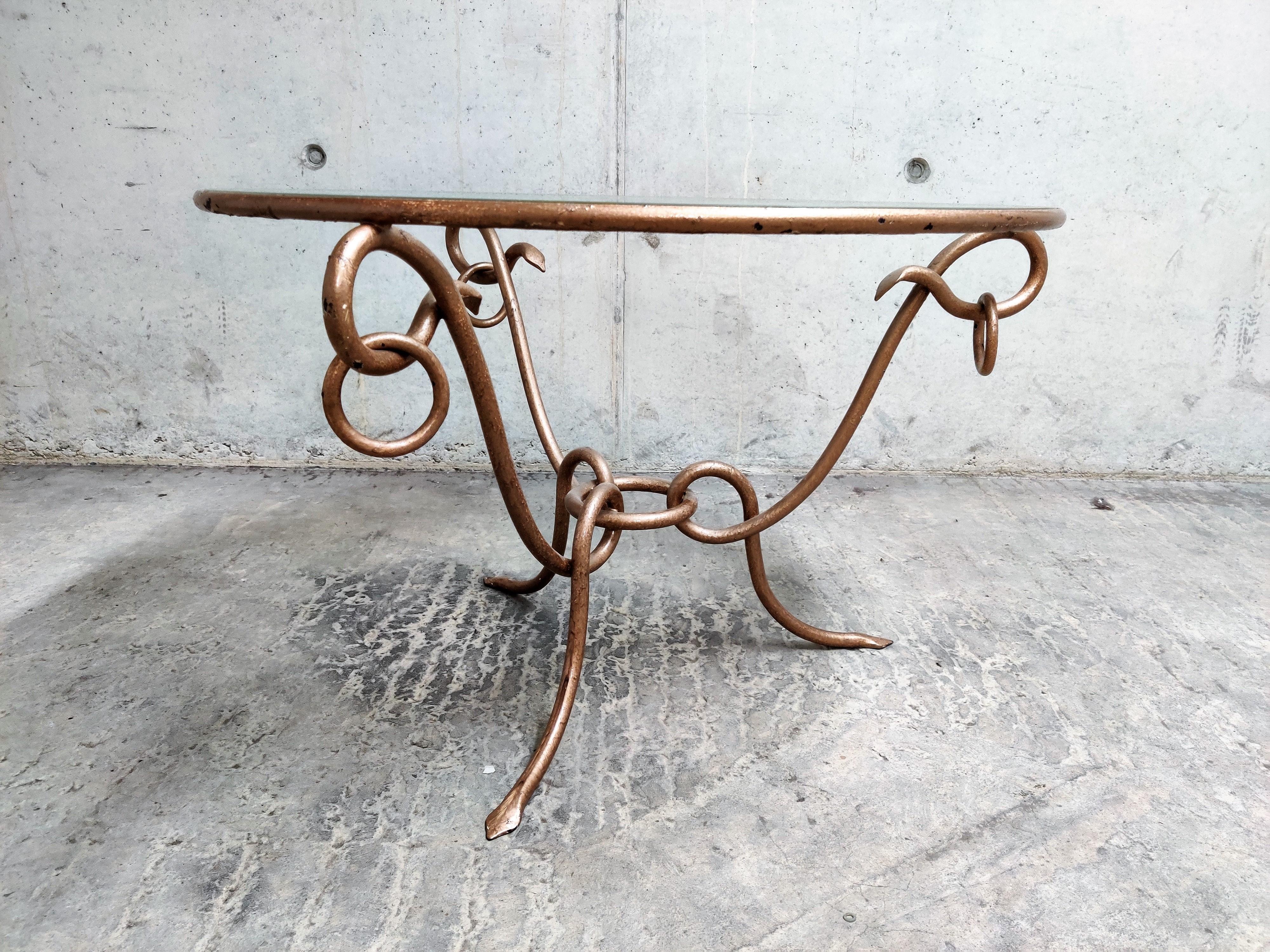 Vintage coffee table designed by René Drouet (1899–1993).

The table has a gilded wrought iron base and the original glass top with a small chip, but not disturbing. We can also provide a new glass if desired.

The base has a beautiful dark red