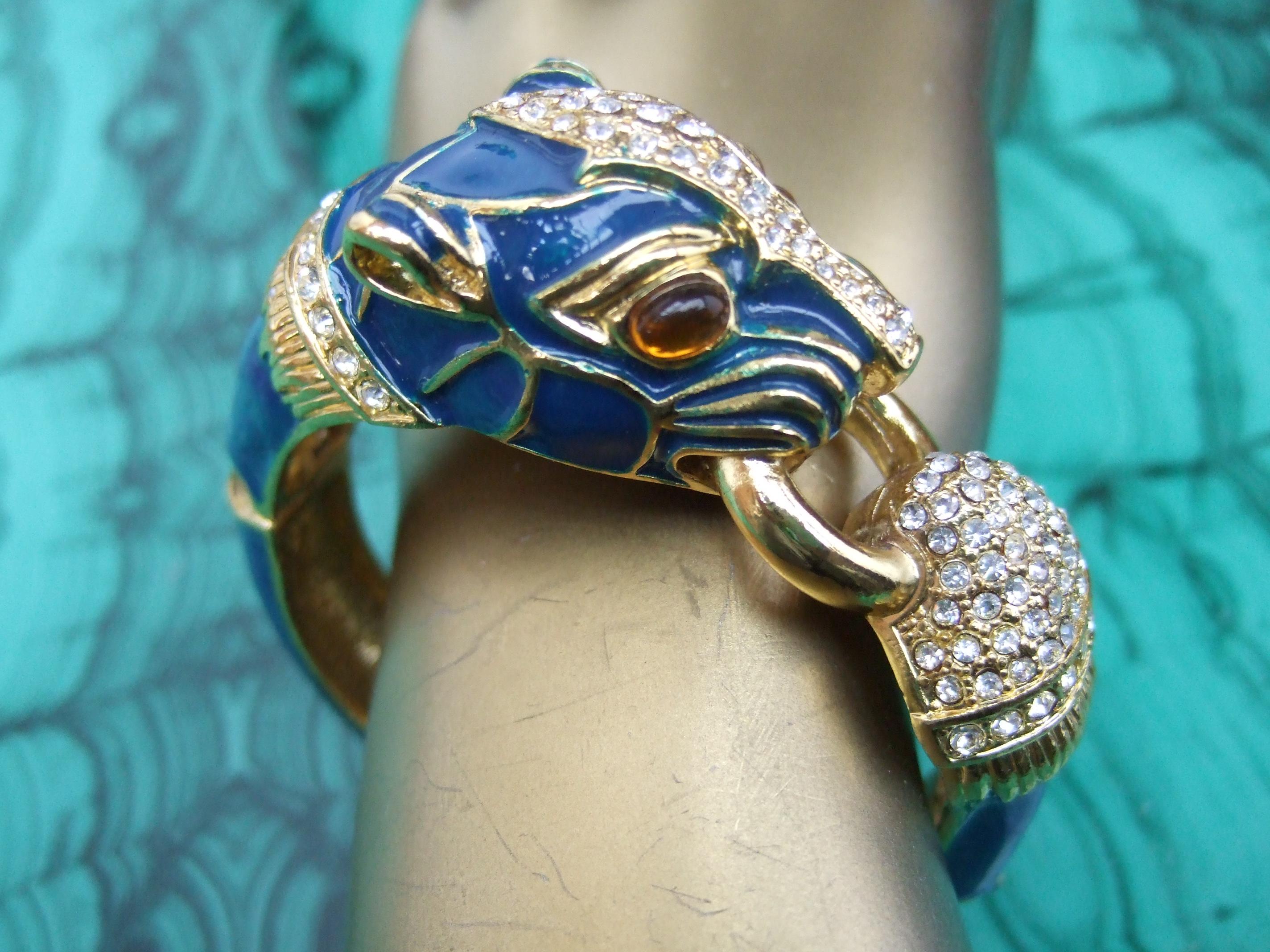 Gilt metal crystal panther jeweled enamel hinged bangle bracelet c 1980s
The elegant bracelet is designed with an exotic panther sheathed in blue enamel
The panther is embellished with amber glass color cabochon eyes 

The panther is designed with a
