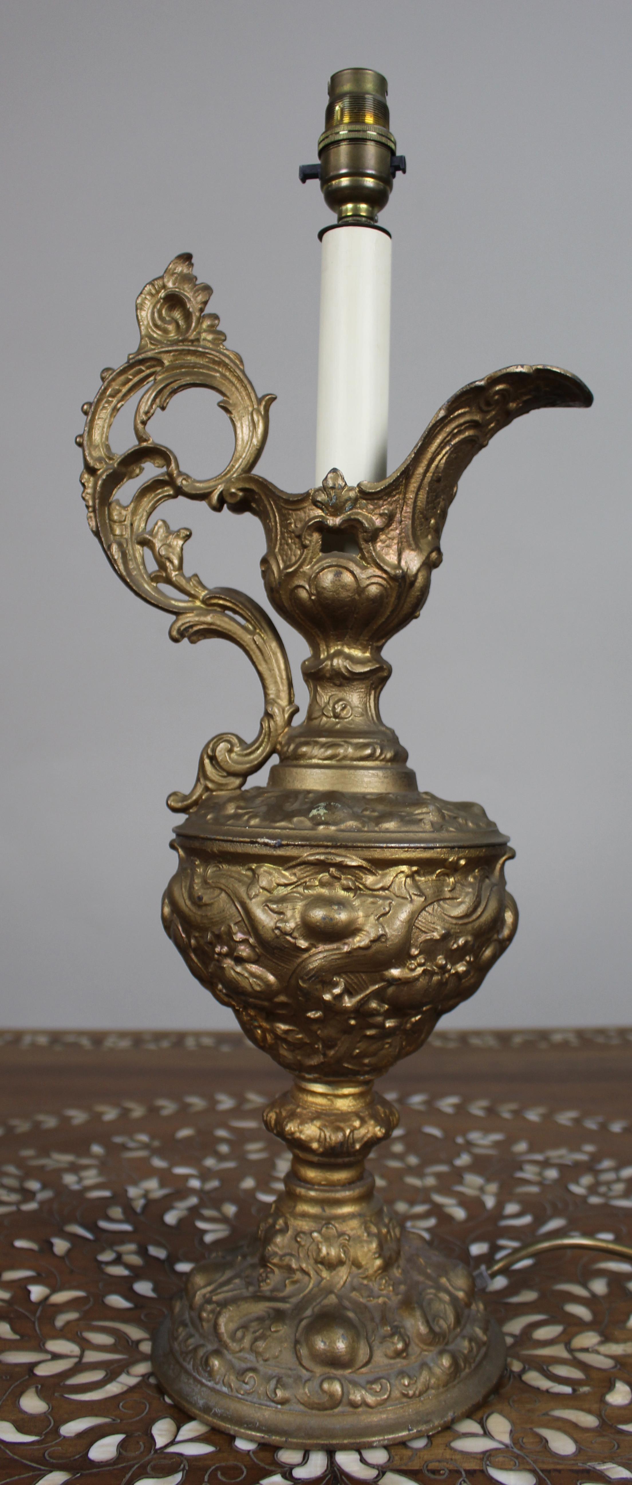 Lampe à aiguière en métal doré, c.1900

Aiguière décorative en métal doré de style néo-rococo, datant d'environ 1900 et transformée par la suite en lampe de table. Le corps est moulé en métal commun (spelter) avec des motifs de feuillage, de fruits