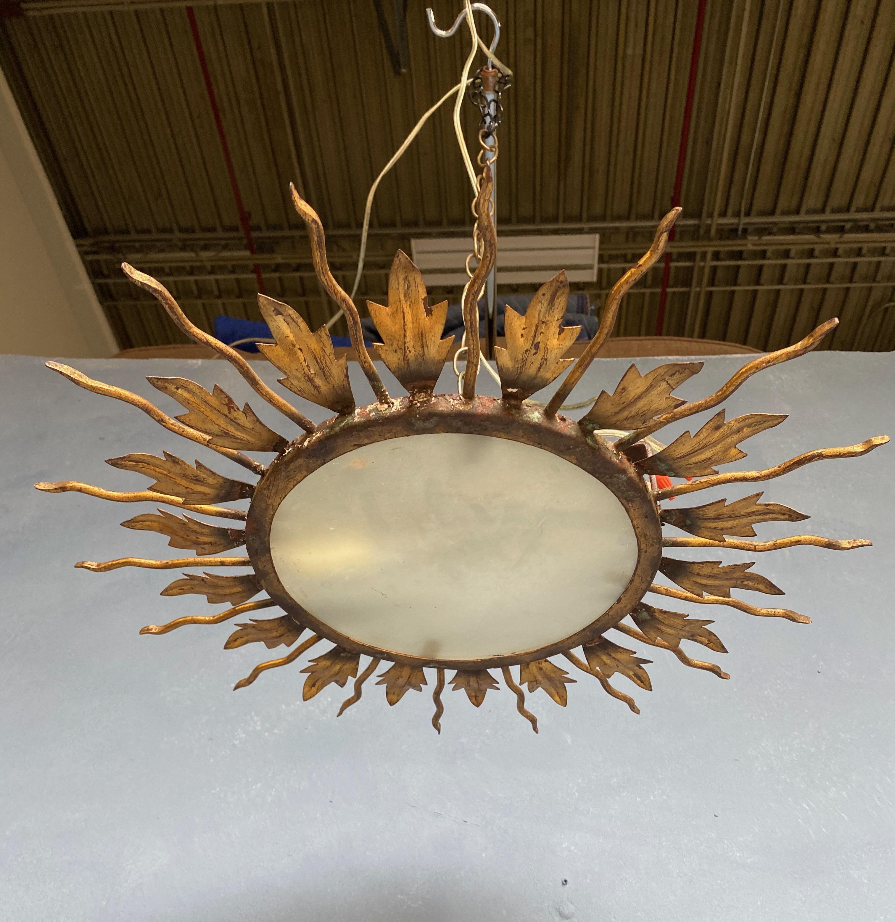  An unusual flush mounted ceiling fixture with two alternating layers of leave and rays joined together on a solid base. The hand applied finish has a rich gold patina over a darker under coat.  This fixture will be wired to accommodate 2 candelabra
