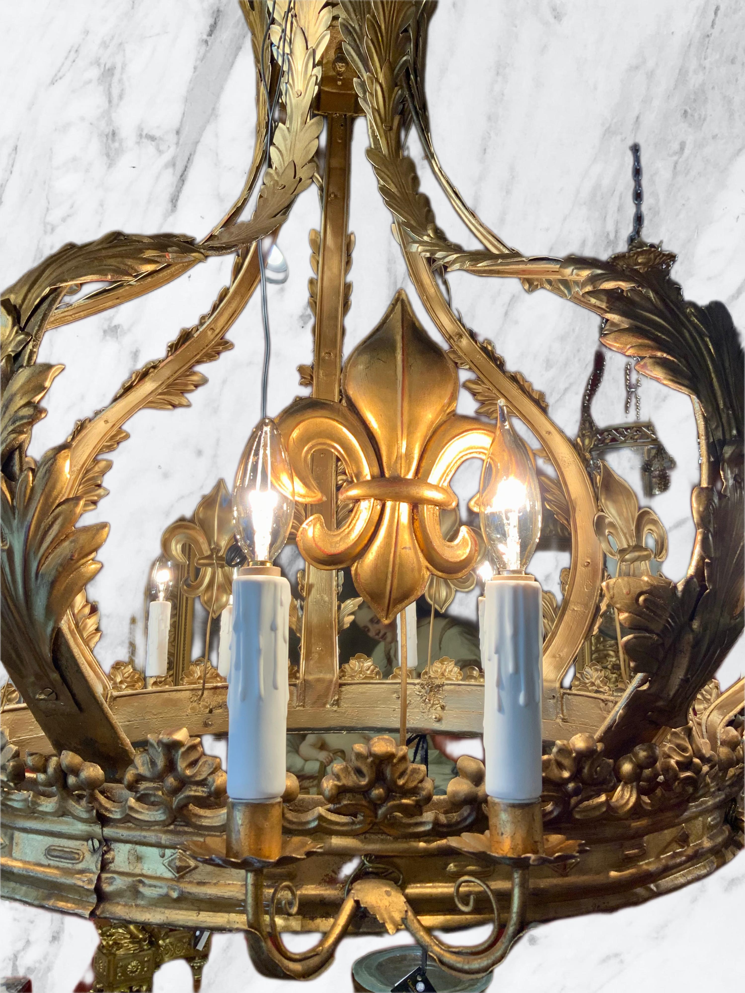 Unique design in a round crown like form is made in a gilt.
Metal. Twelve lights surround the outer ring of this exceptional. 
Chandelier. A design in the form of the fleur d lis design.
Is positioned between the candles. The shape of this