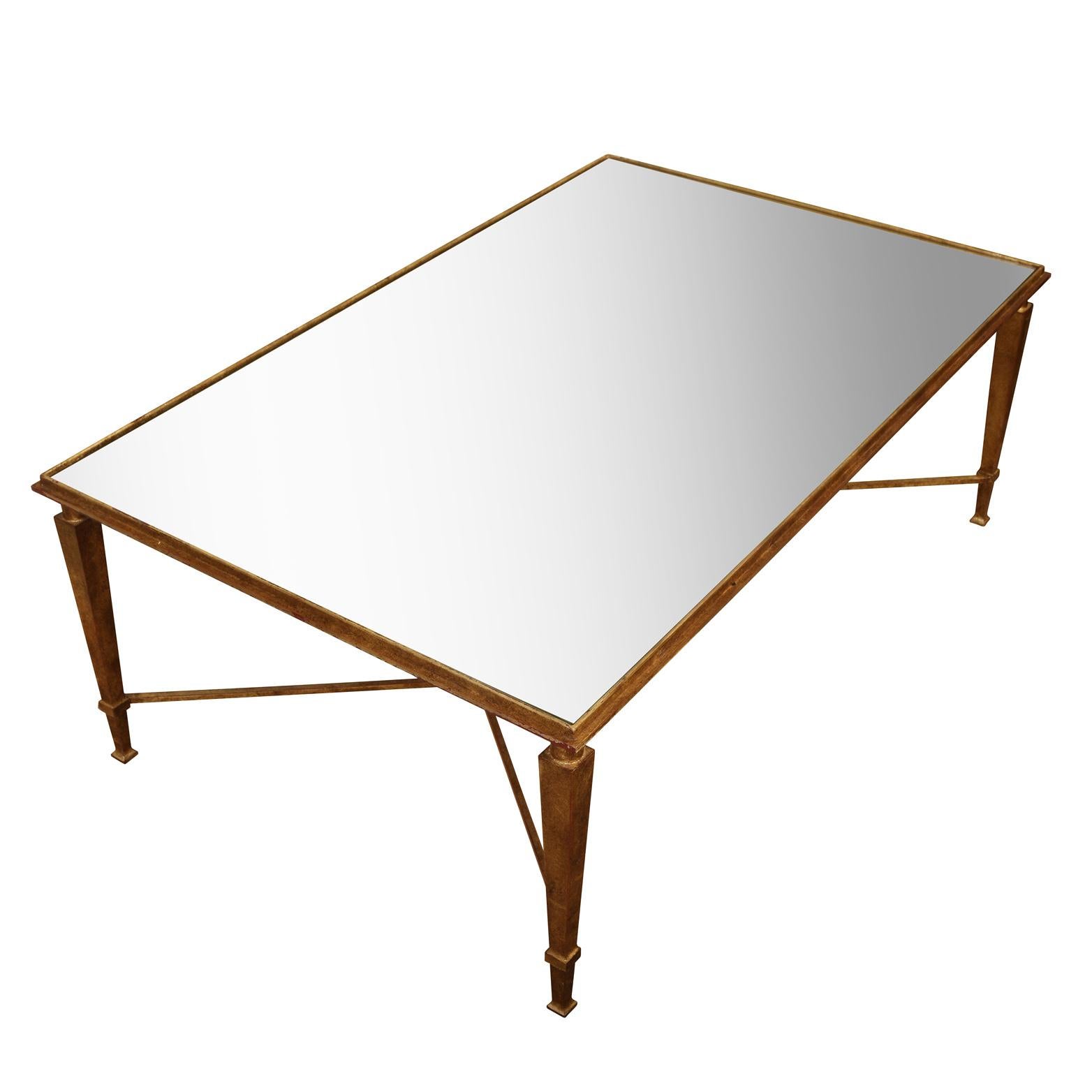 French style gilt metal coffee table with inset mirrored top and geometric X base and tapered legs.