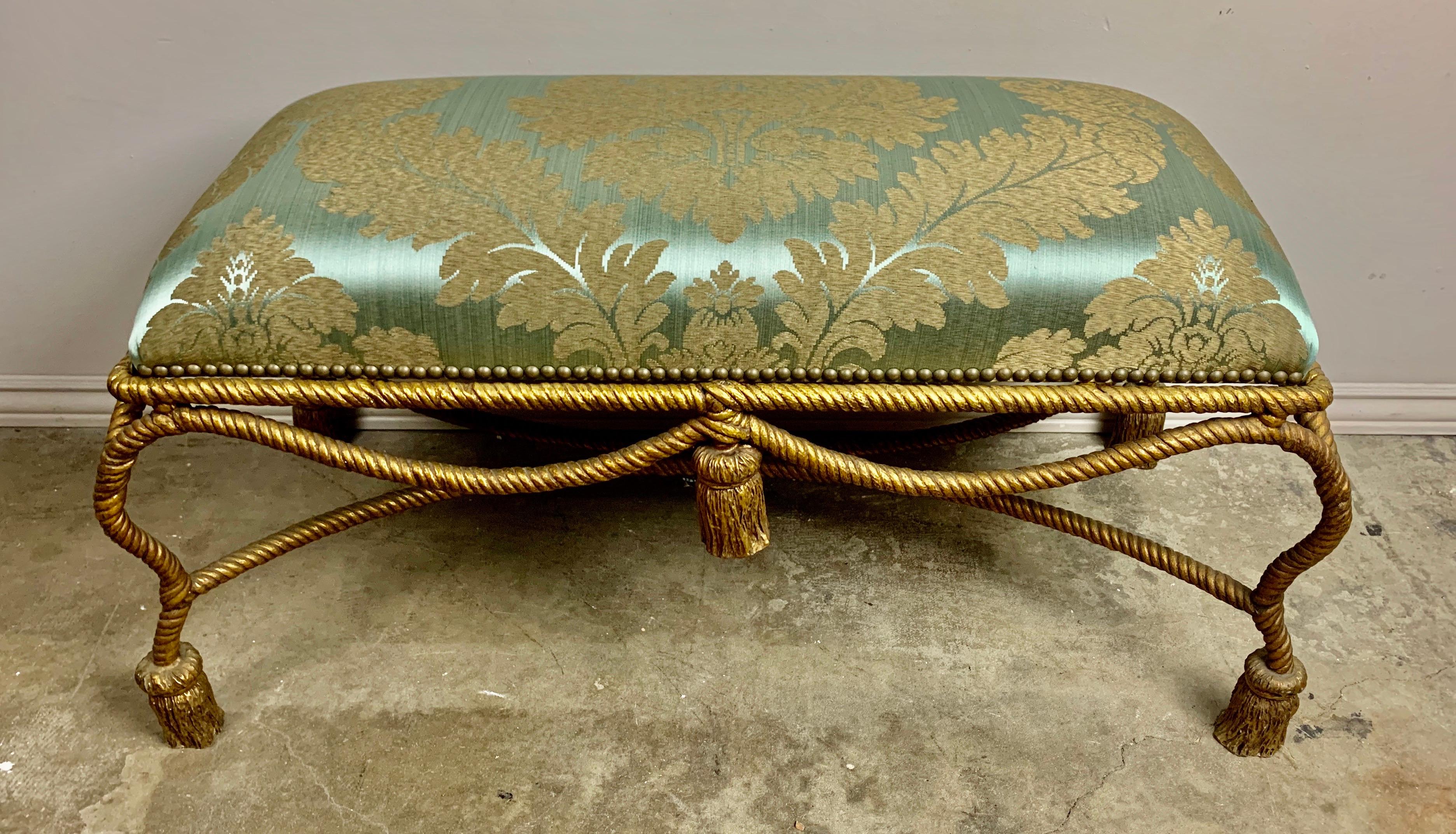 French gilt metal rope and tassel bench. The bench is newly upholstered in
an aqua silk damask with golden leaf decoration.