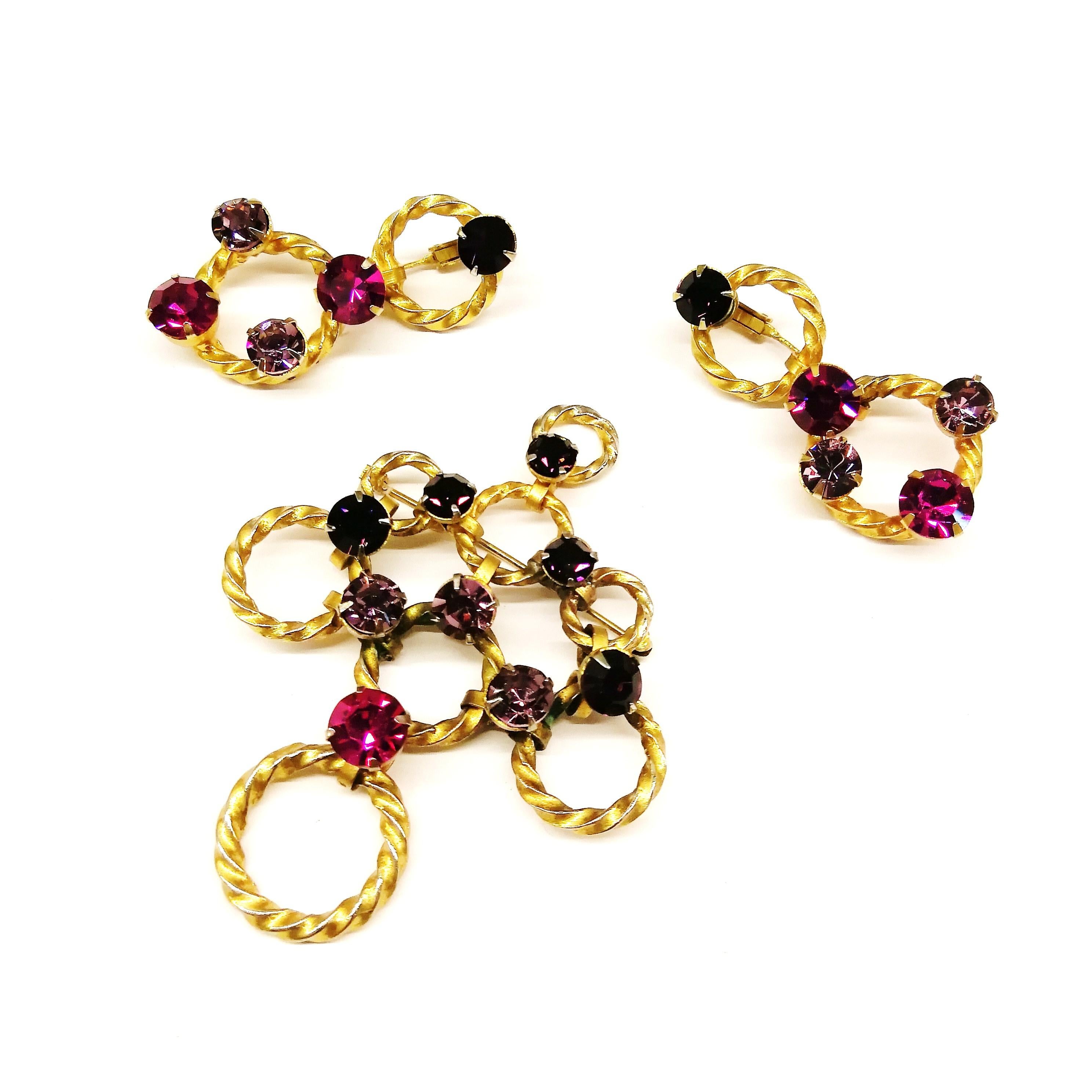 An unusual brooch and earrings from Christian Dior by Mitchel Maer, made of articulated twisted gilt rings of various sizes, highlighted with amethyst, light amethyst and fuschia pastes, both earrings and brooches are articulated. A structured