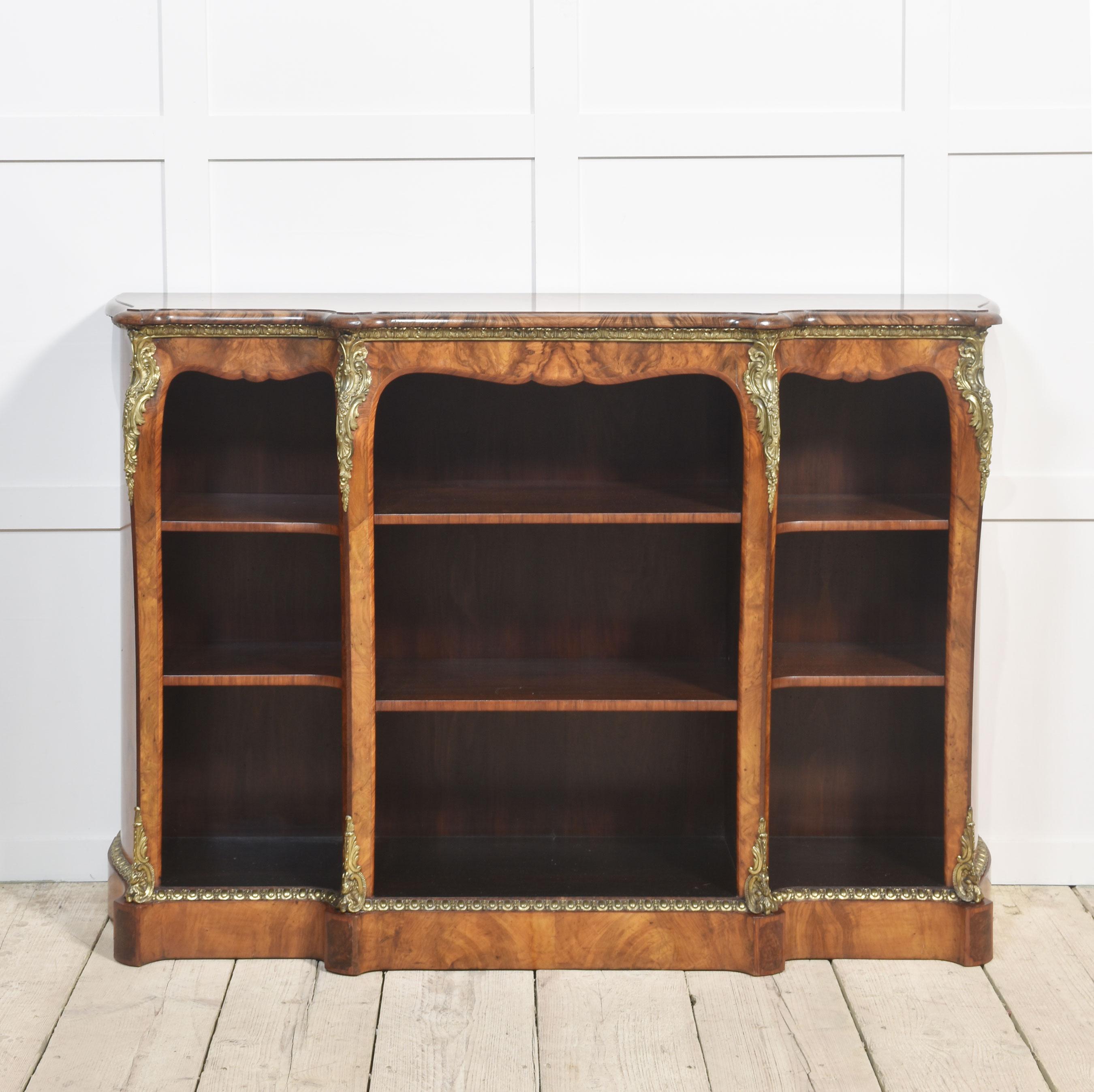 Libreria a giorno a fasce incrociate in noce figurato del XIX secolo, con design Luigi XV. Il piano frontale ha un bordo modellato, su un contorno sagomato e diviso, con tre banchi di ripiani regolabili, ogni sezione ha due ripiani. Sollevato su una