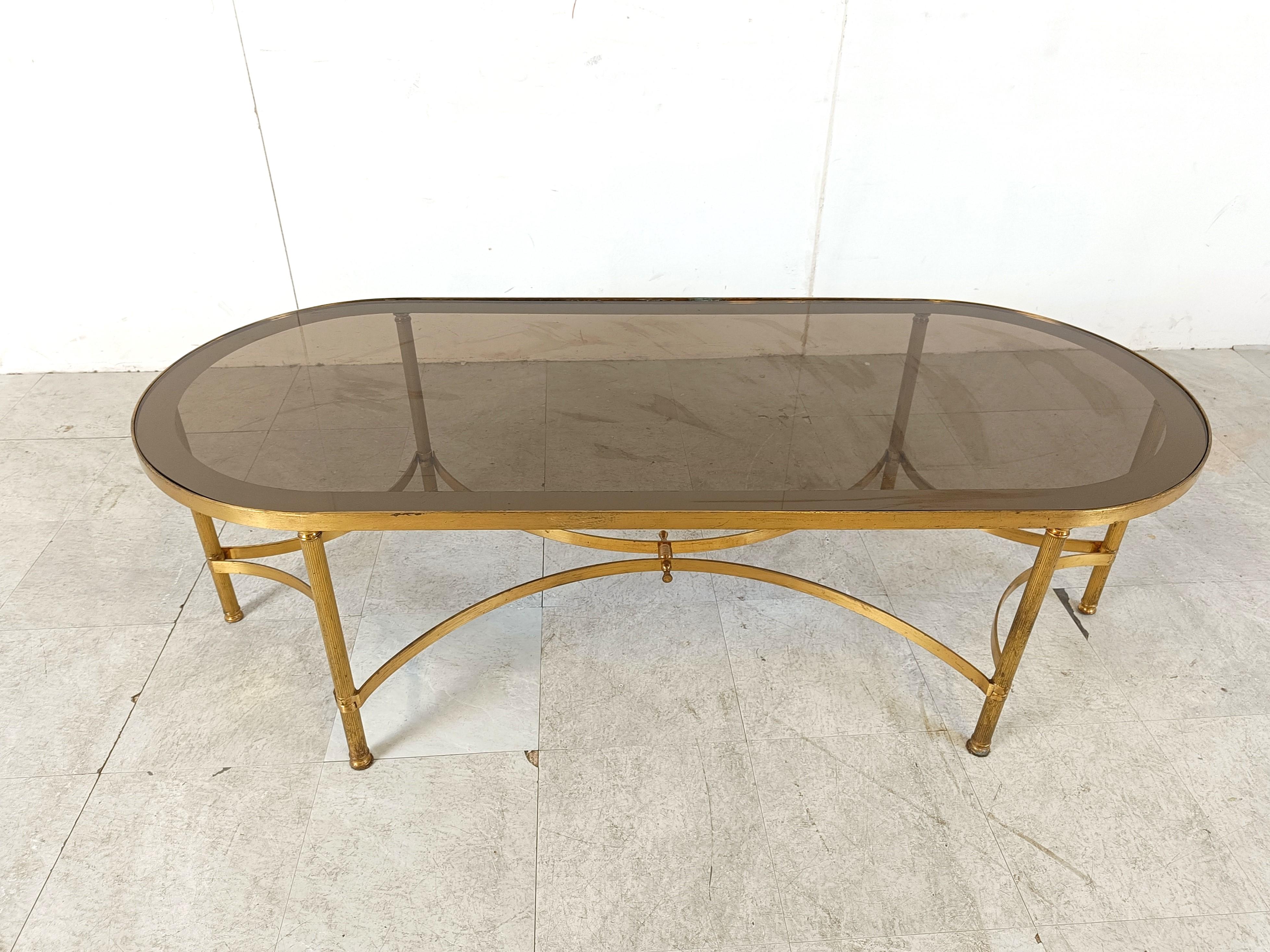 
Neoclassical oval coffee table with a gilt metal frame and smoked glass top in the manner of Maison Jansen.

Playful design with the bent metal between the legs.

1960s - France

Good condition

Dimensions:
Height: 46cm/18.11”
Width: