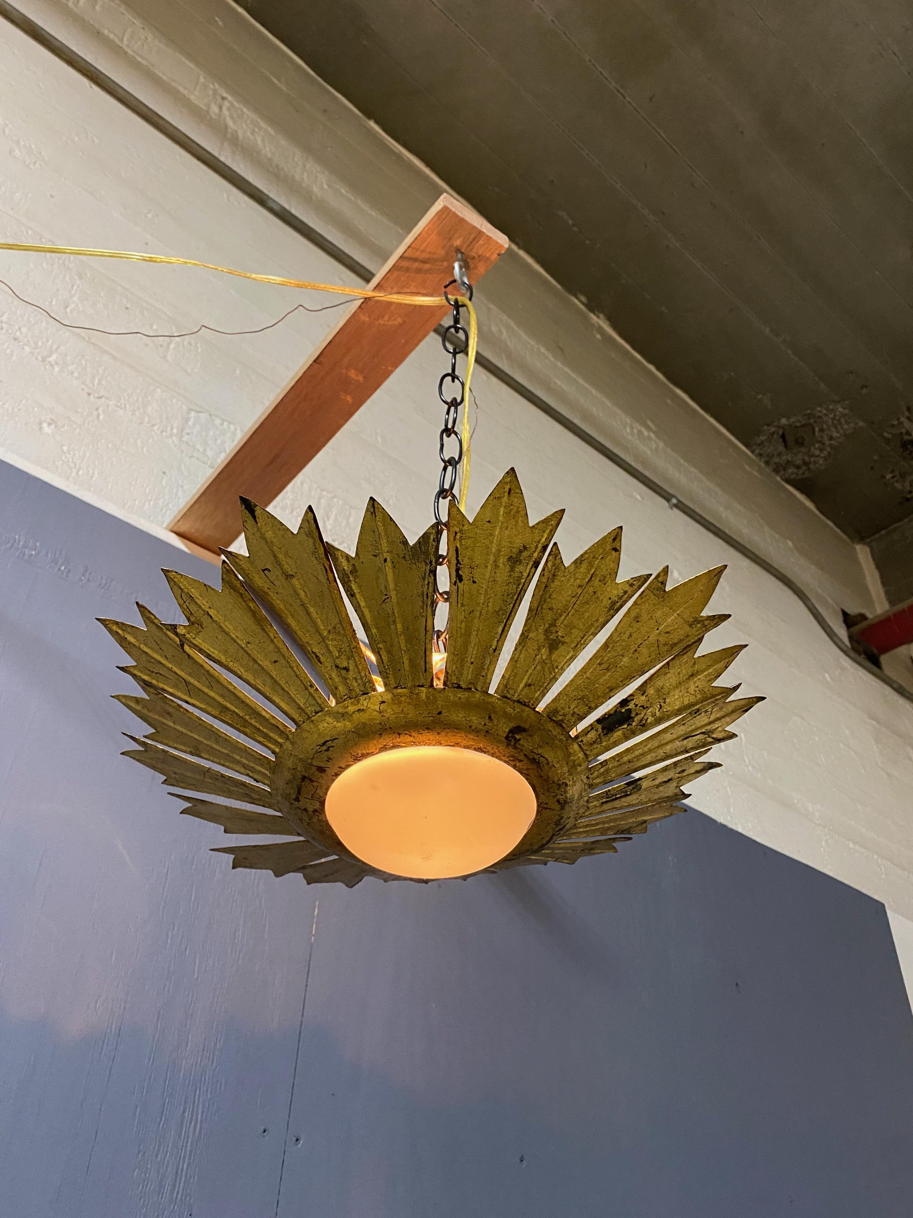 This stunning flush mount ceiling fixture has a striking modern design. The gilt metal painted rays that surround the convex white opaline globe create a remarkable effect that is truly eye-catching. While most Spanish ceiling fixtures from this
