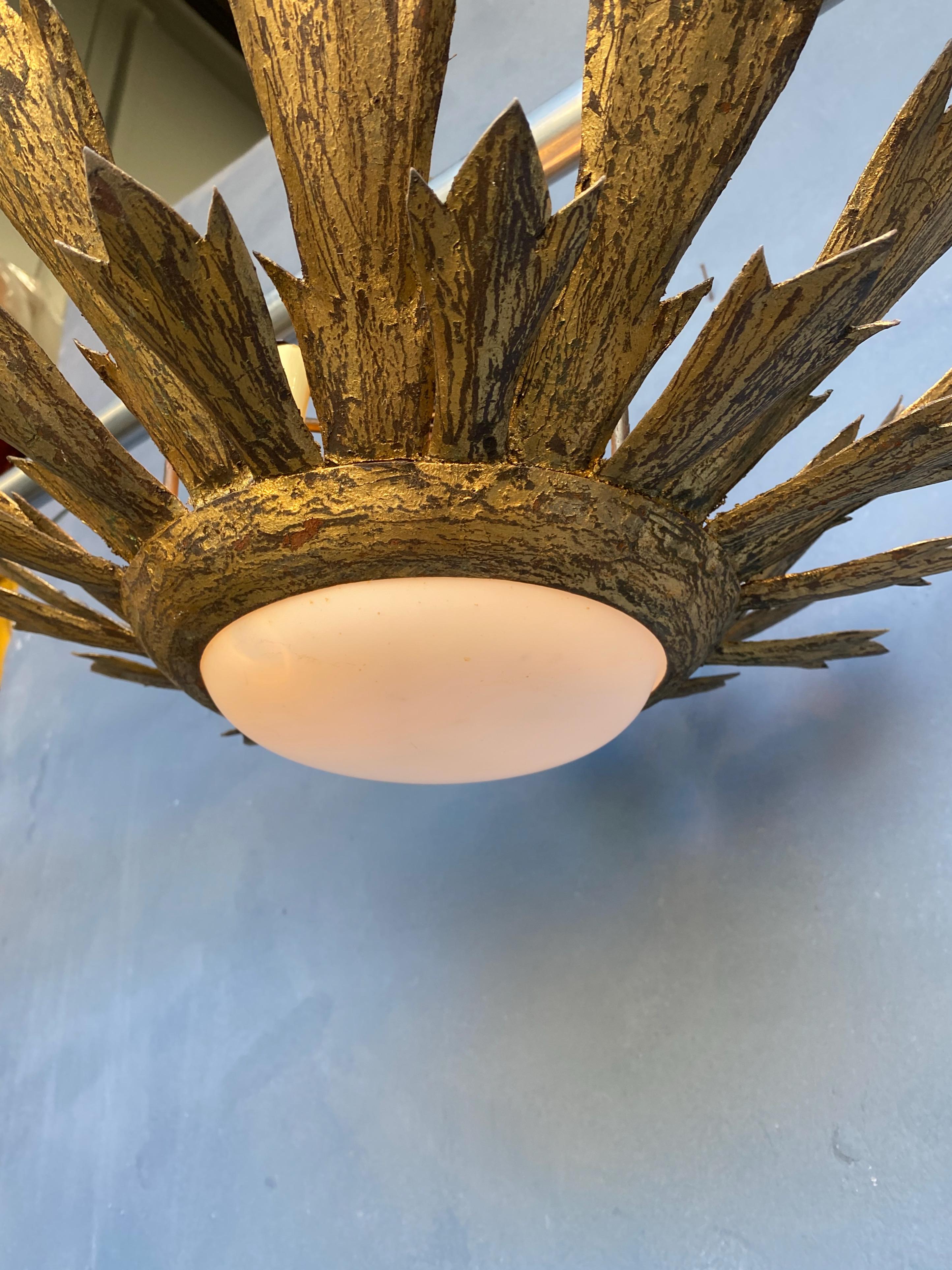 This unique flush mount ceiling fixture is defined by its radiating stylized leaves. Composed of two tiers of pointed leaves - a larger one and a smaller one, they're joined at the base with an expansive decorative band. The original central globe