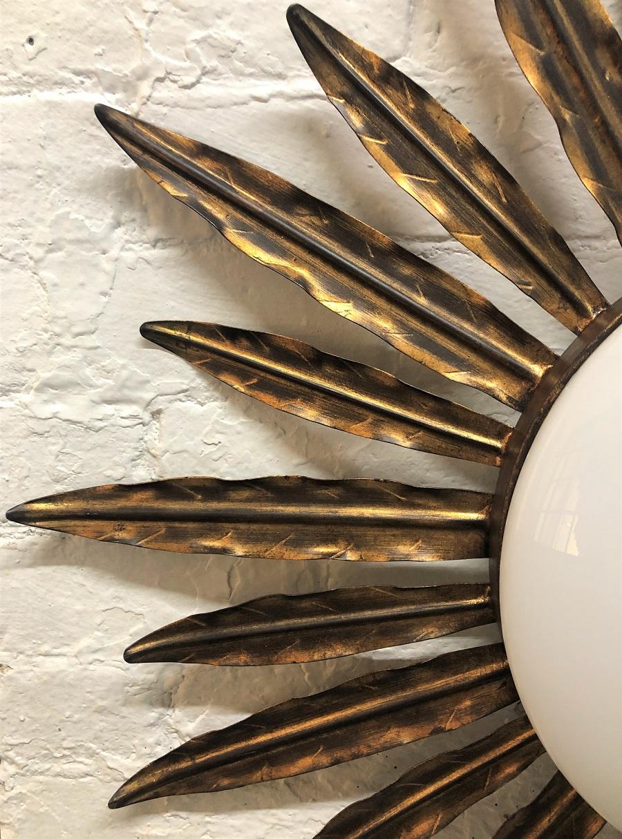 Gilt sunburst light fixture. The light fixture has a frosted glass dome with a gilt metal frame. Can also be used as a wall sconce.