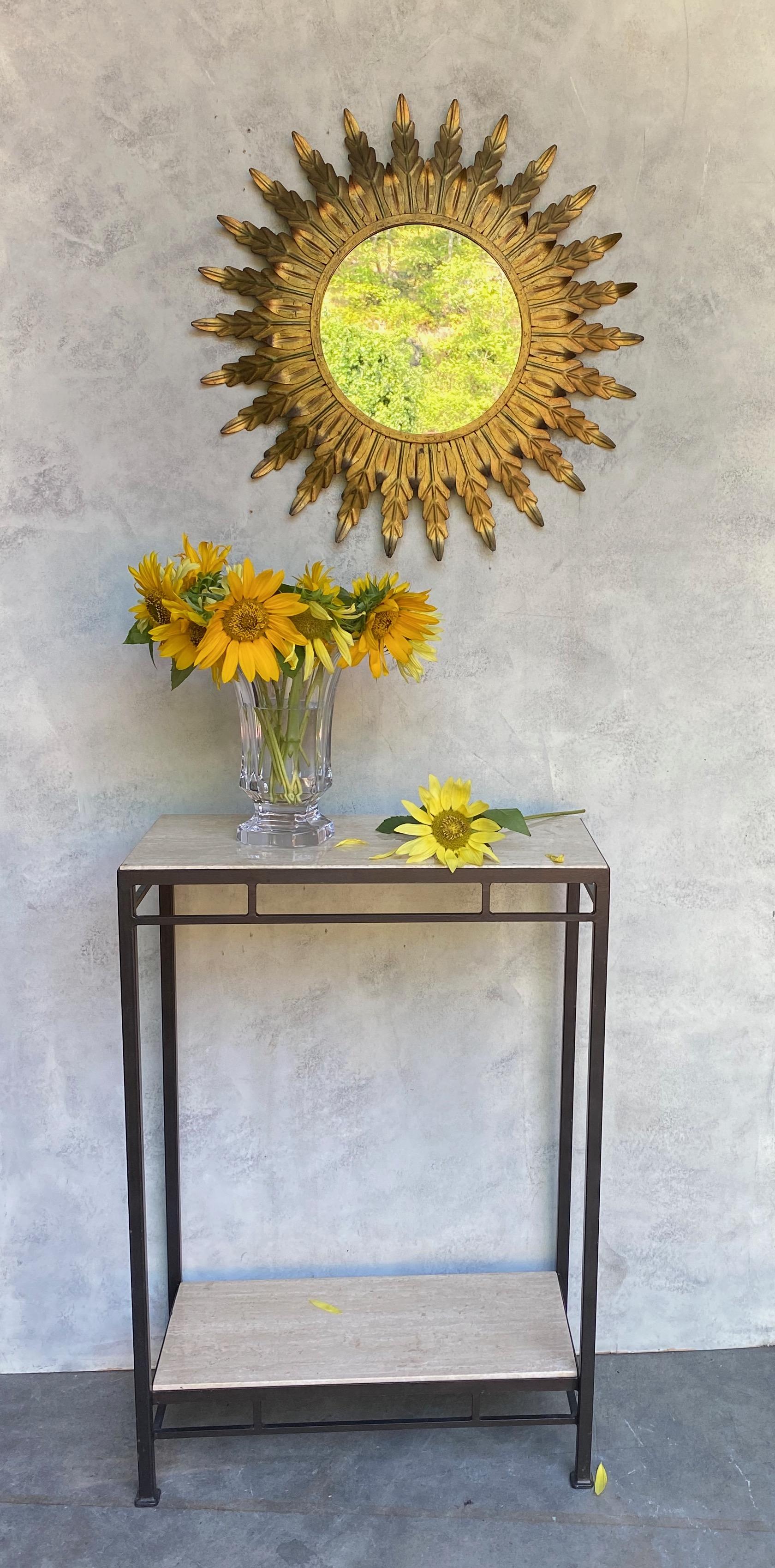 Spanish gilt metal mirror with closely joined sunburst rays as stylized leaves around a solid border. We recently added a felt backing to the mirror to give it more protection and a finished look. Spanish 1950's. Very good vintage condition. 
 