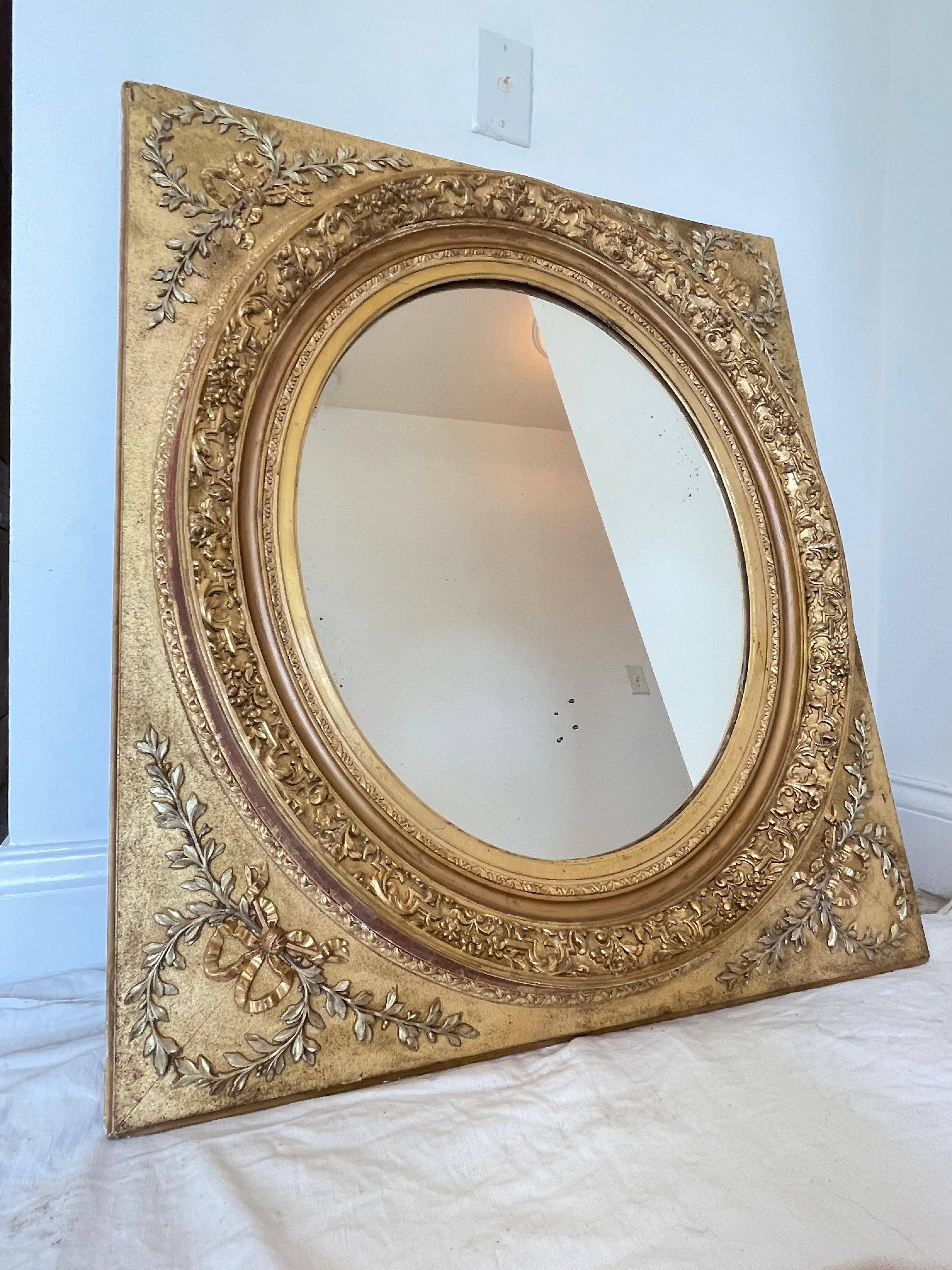 Pretty mirror in gilded wood of Napoleon 3 era. Mirror in the shape of a medallion has foliage and ribbon on the corners. Around the oval mercury mirror, friezes richly garnished with garlands of flowers.