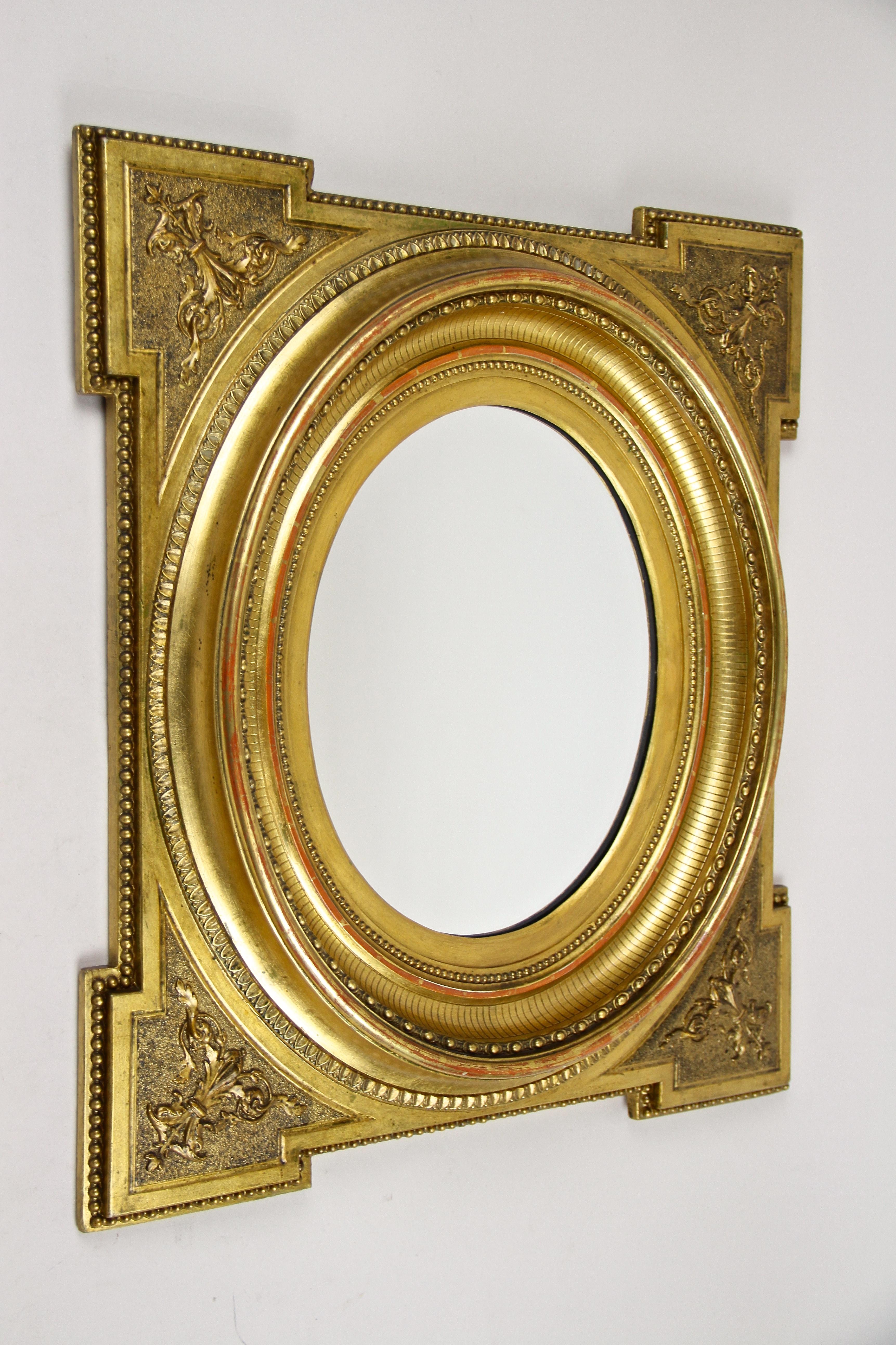 Superb gilt oval Biedermeier wall mirror from the second period around 1860 in Austria. Standing out with an incredible design, this unique late Biedermeier mirror impresses with slightly protruding corners adorned by beautiful stucco ornamentations