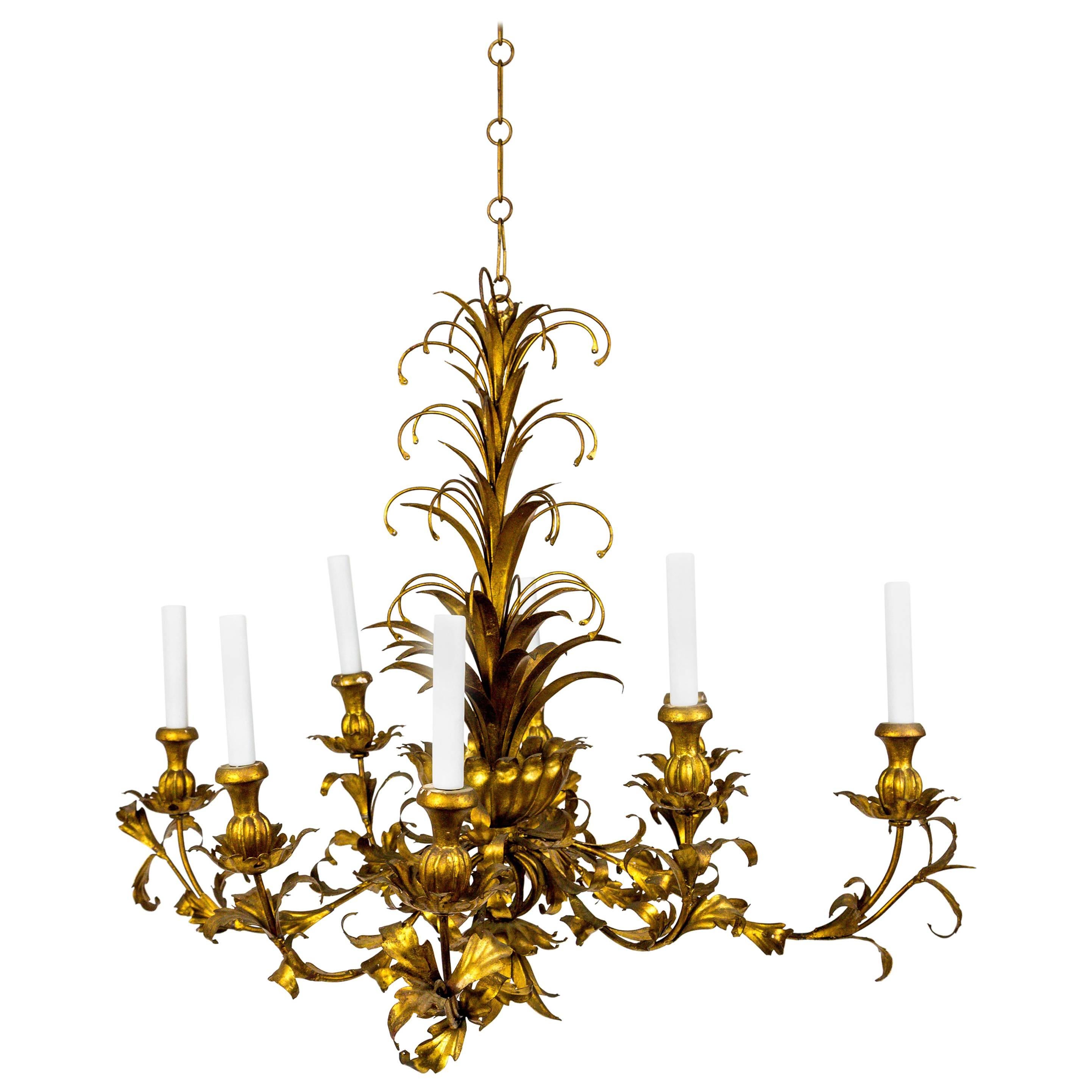 We have two of these opulent, gilt metal, Hollywood Regency chandeliers. The finish has a rich, gleaming tone, and the unique shape changes from various points of view. From below, a rectangular shape is noticeable as four of the eight arms stretch